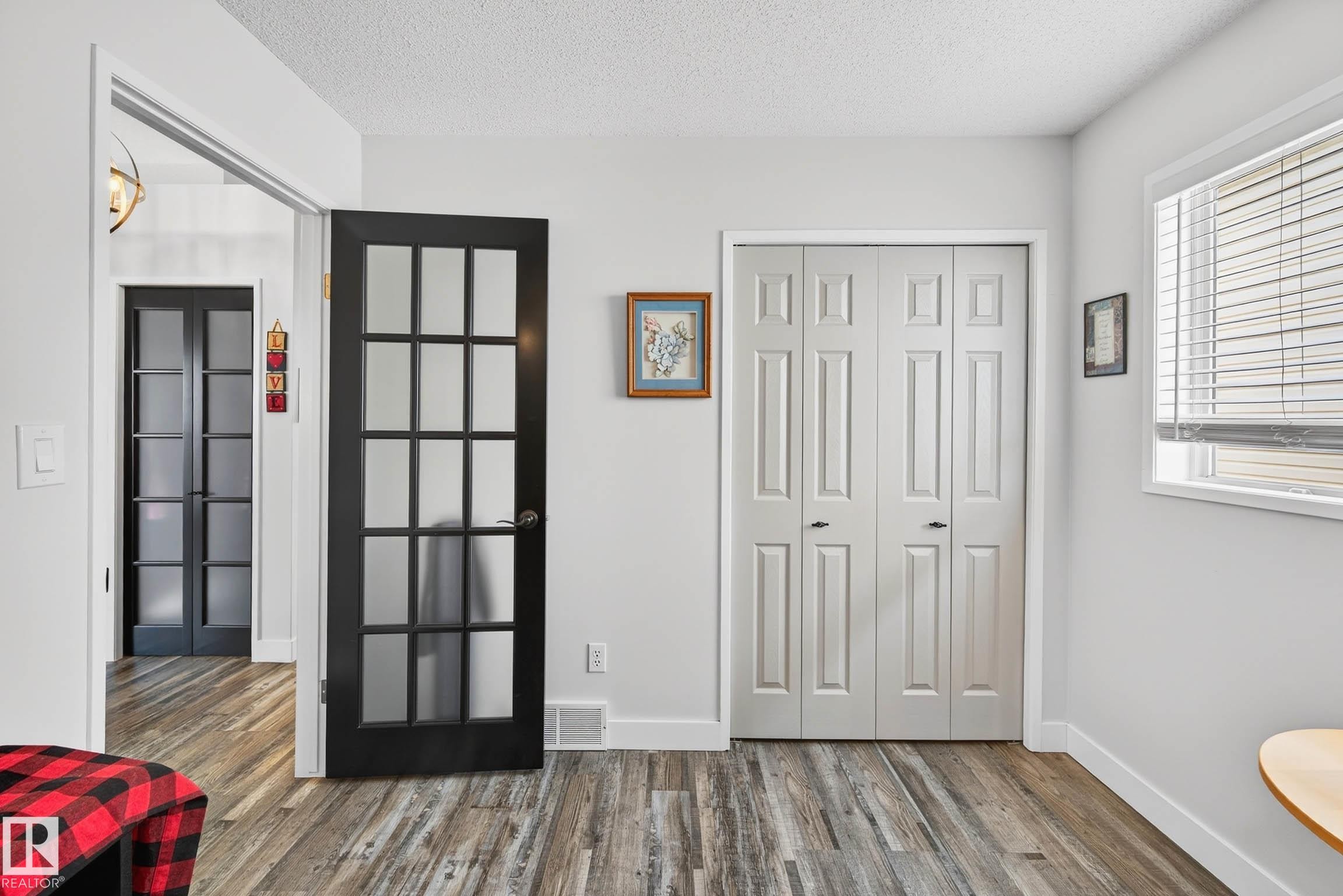 The room features wide plank flooring, a window with blinds, and white bi-fold closet doors - 34 Donald Place, St. Albert, AB - Indoor Photo Showing Other Room