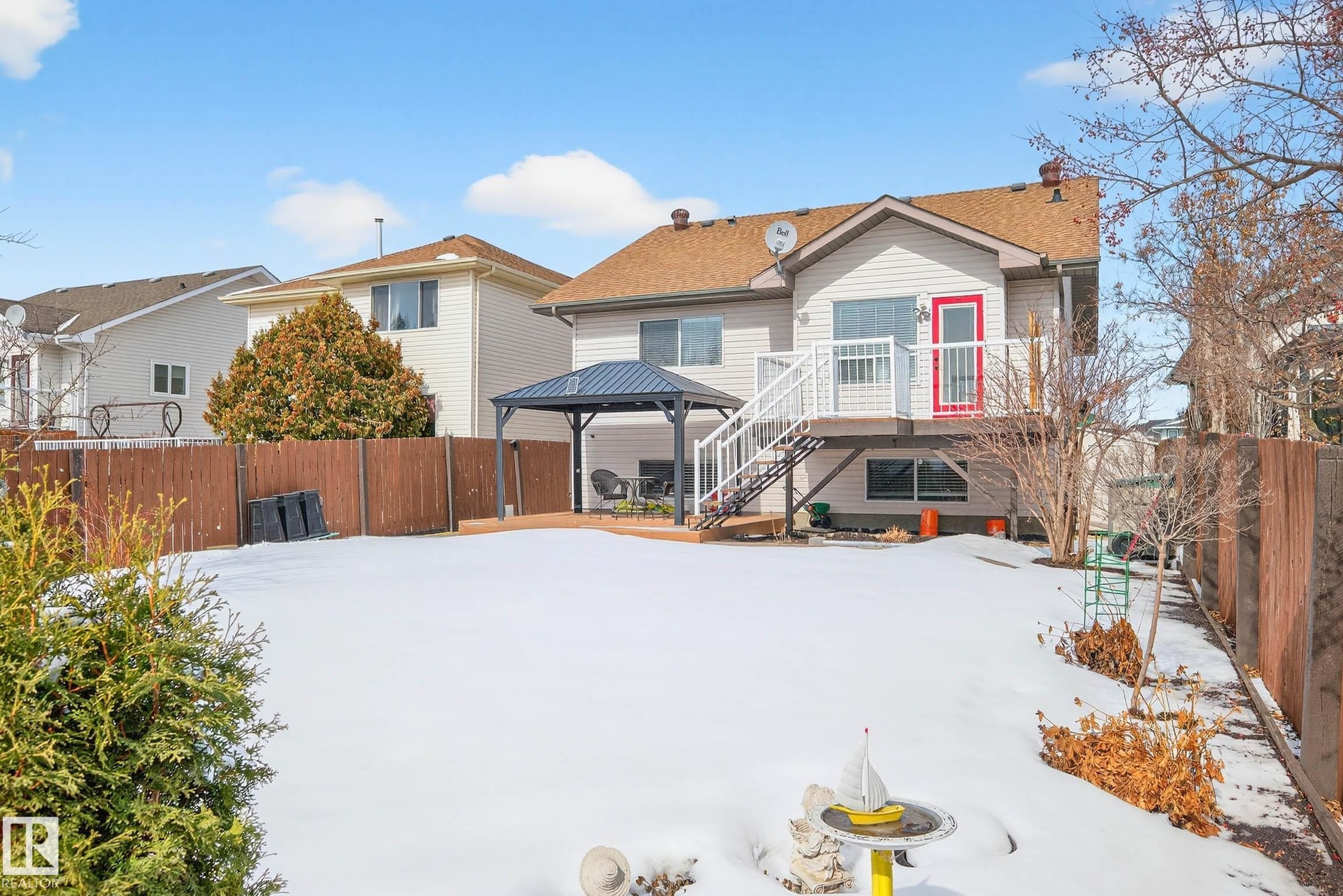 The property features a fenced backyard with a snow-covered lawn, a raised deck with white railings, and a gazebo on a wooden patio - 34 Donald Place, St. Albert, AB - Outdoor