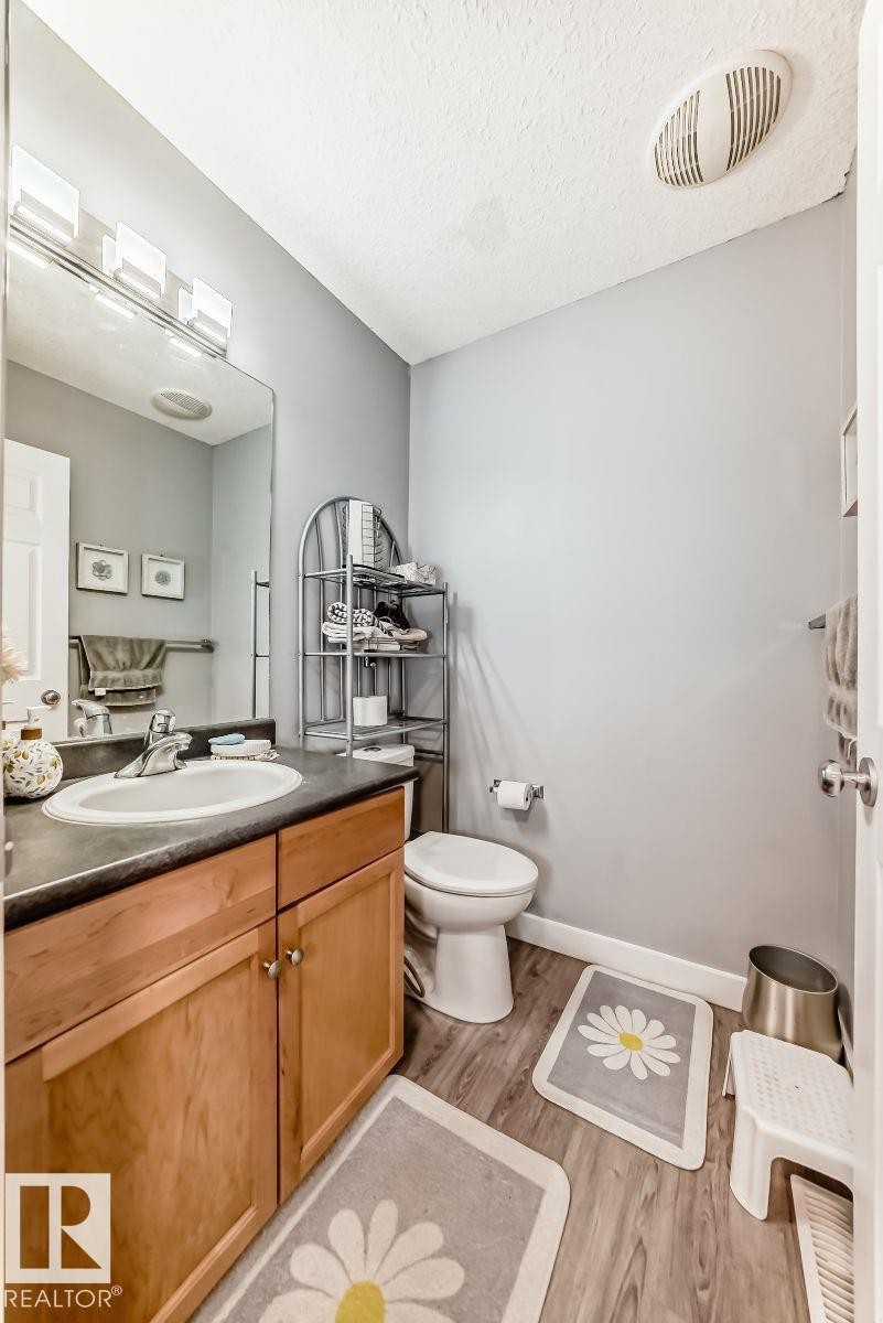 Bathroom featuring a wood-finish vanity with an integrated sink, dark countertop, and brushed nickel faucet - 715 Hudson Place, Edmonton, AB - Indoor Photo Showing Bathroom