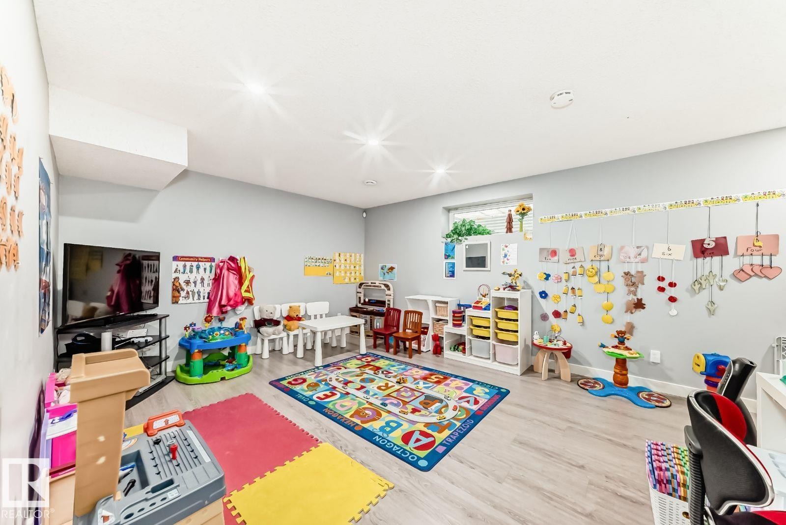 Spacious room featuring light wood-finish flooring, recessed lighting, a single window, light gray wall paint, and a soffit detail - 715 Hudson Place, Edmonton, AB - Indoor Photo Showing Other Room