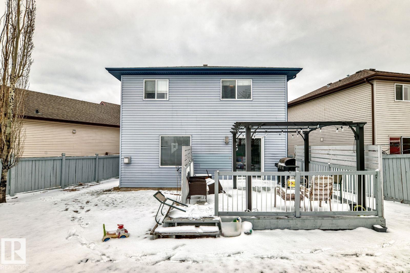 Rear exterior featuring light blue siding, a multi-level wood-finish deck with railing, and a dark-toned pergola - 715 Hudson Place, Edmonton, AB - Outdoor With Exterior