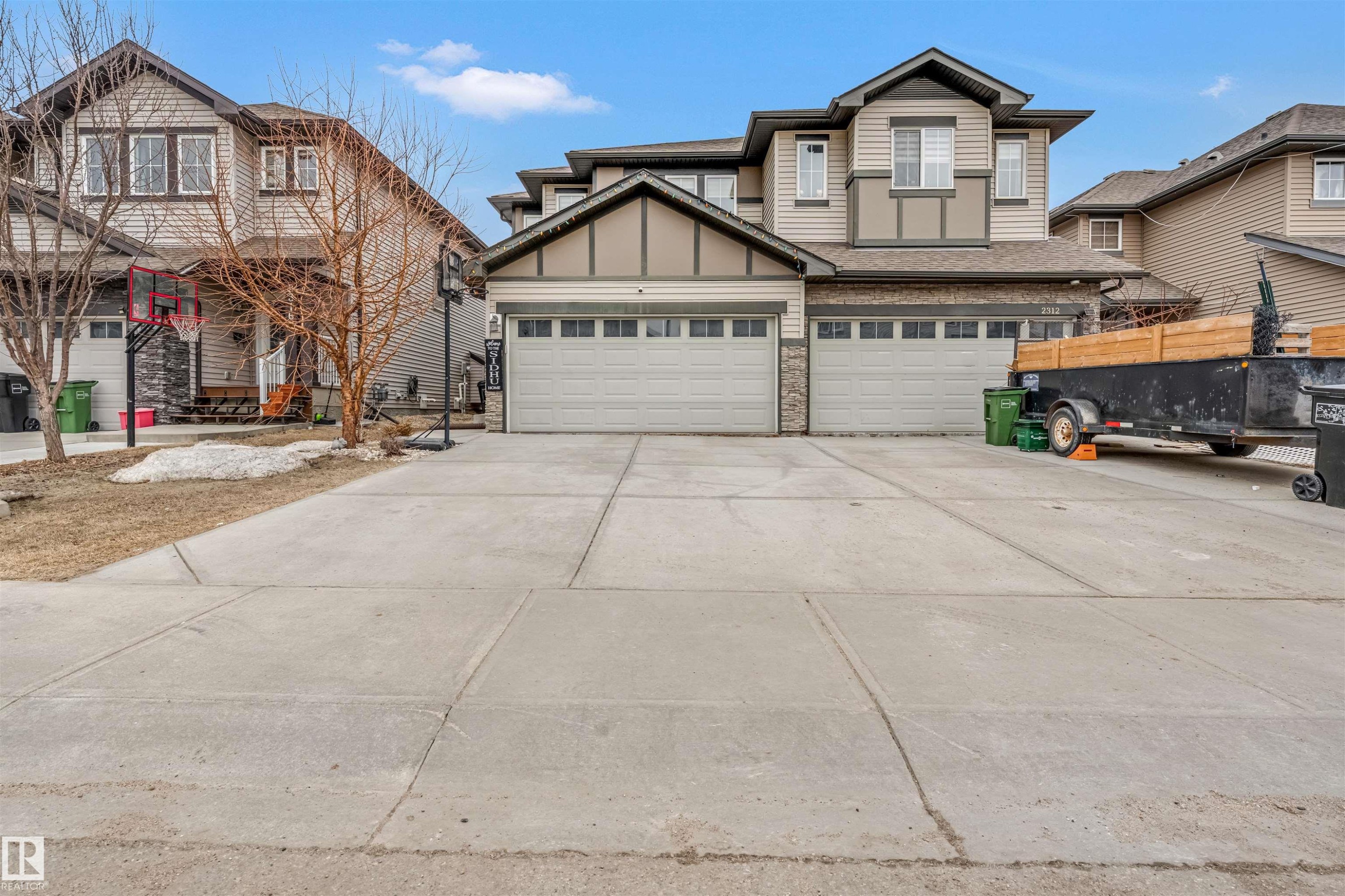 Traditional-style architecture featuring light-colored siding, a two-car garage with individual doors, and a concrete driveway - 2314 22 Avenue, Edmonton, AB - Outdoor With Facade
