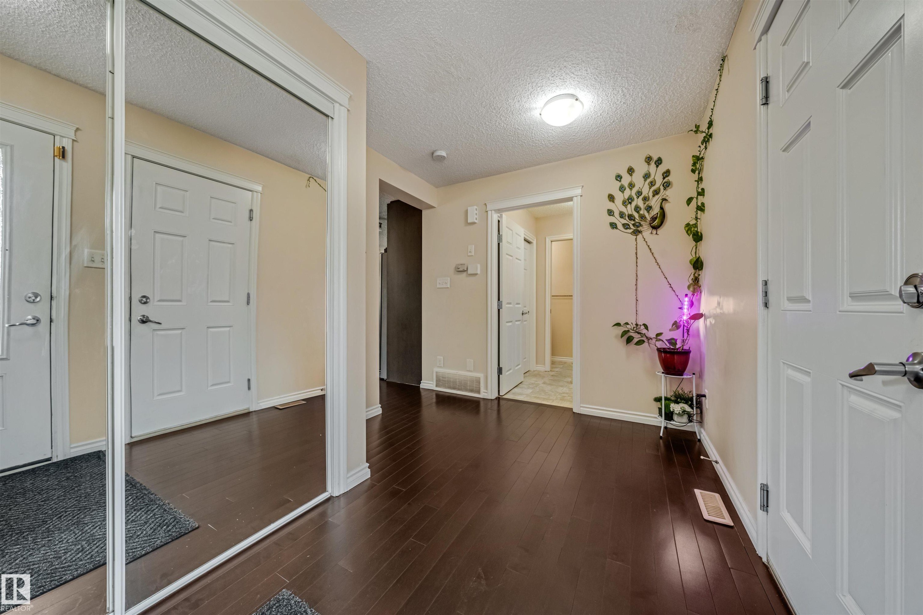 Entryway featuring dark wood-finish flooring, light neutral wall tones, white trim, and a full-length mirrored closet door - 2314 22 Avenue, Edmonton, AB - Indoor Photo Showing Other Room