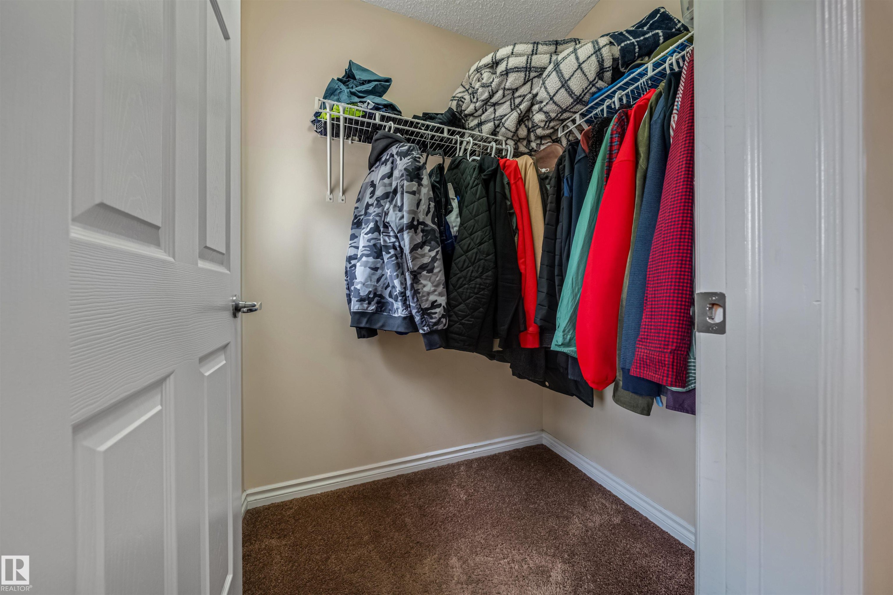 Walk-in closet featuring neutral-toned walls, white trim, and brown carpeting - 2314 22 Avenue, Edmonton, AB - Indoor With Storage