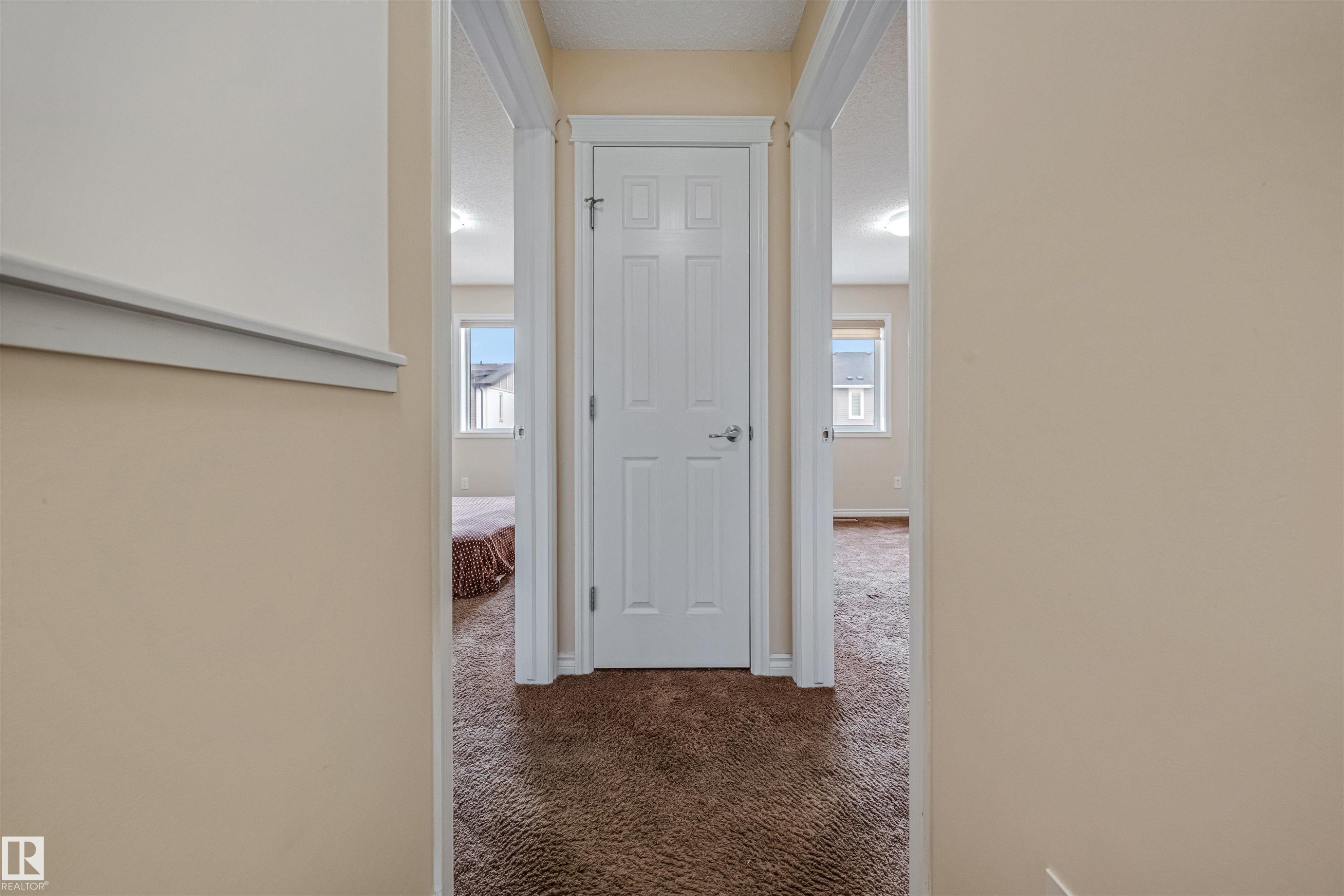 Carpeted hallway featuring a white paneled door, light beige wall paint, and white trim - 2314 22 Avenue, Edmonton, AB - Indoor Photo Showing Other Room