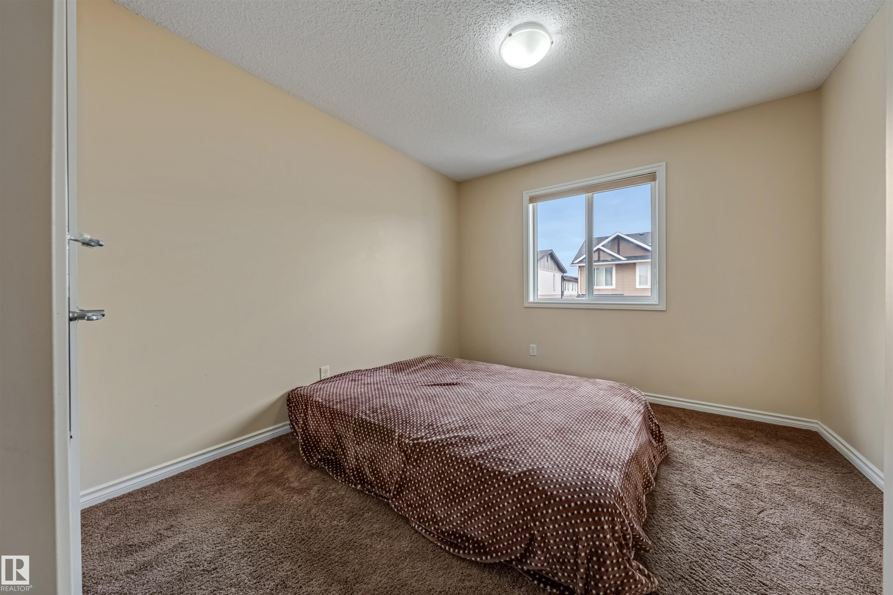 Neutral-toned room featuring a double-paned window, soft brown carpeting, and white baseboards - 2314 22 Avenue, Edmonton, AB - Indoor Photo Showing Bedroom
