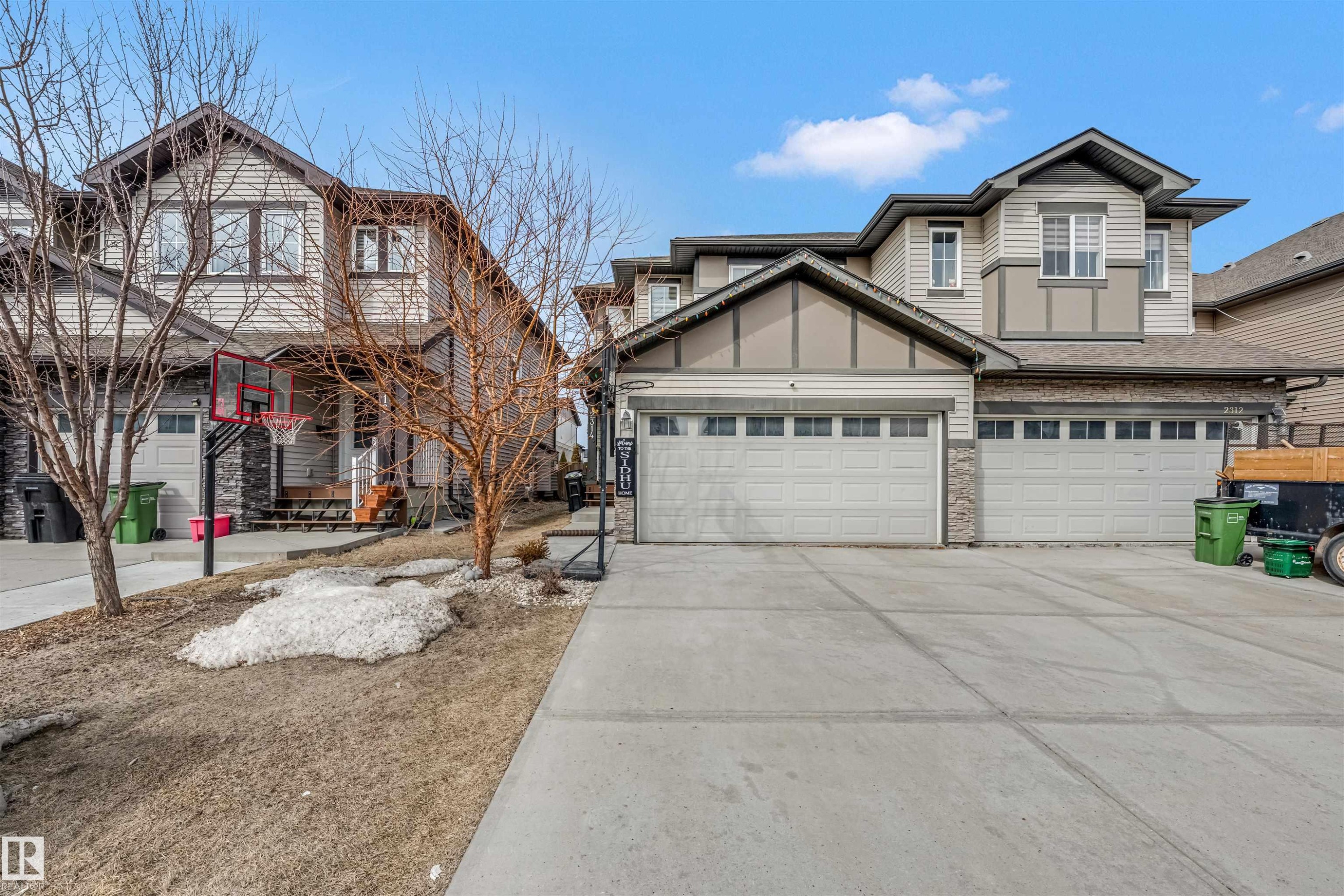 Exterior featuring two prominent garage doors, stone accents, and horizontal siding - 2314 22 Avenue, Edmonton, AB - Outdoor With Facade