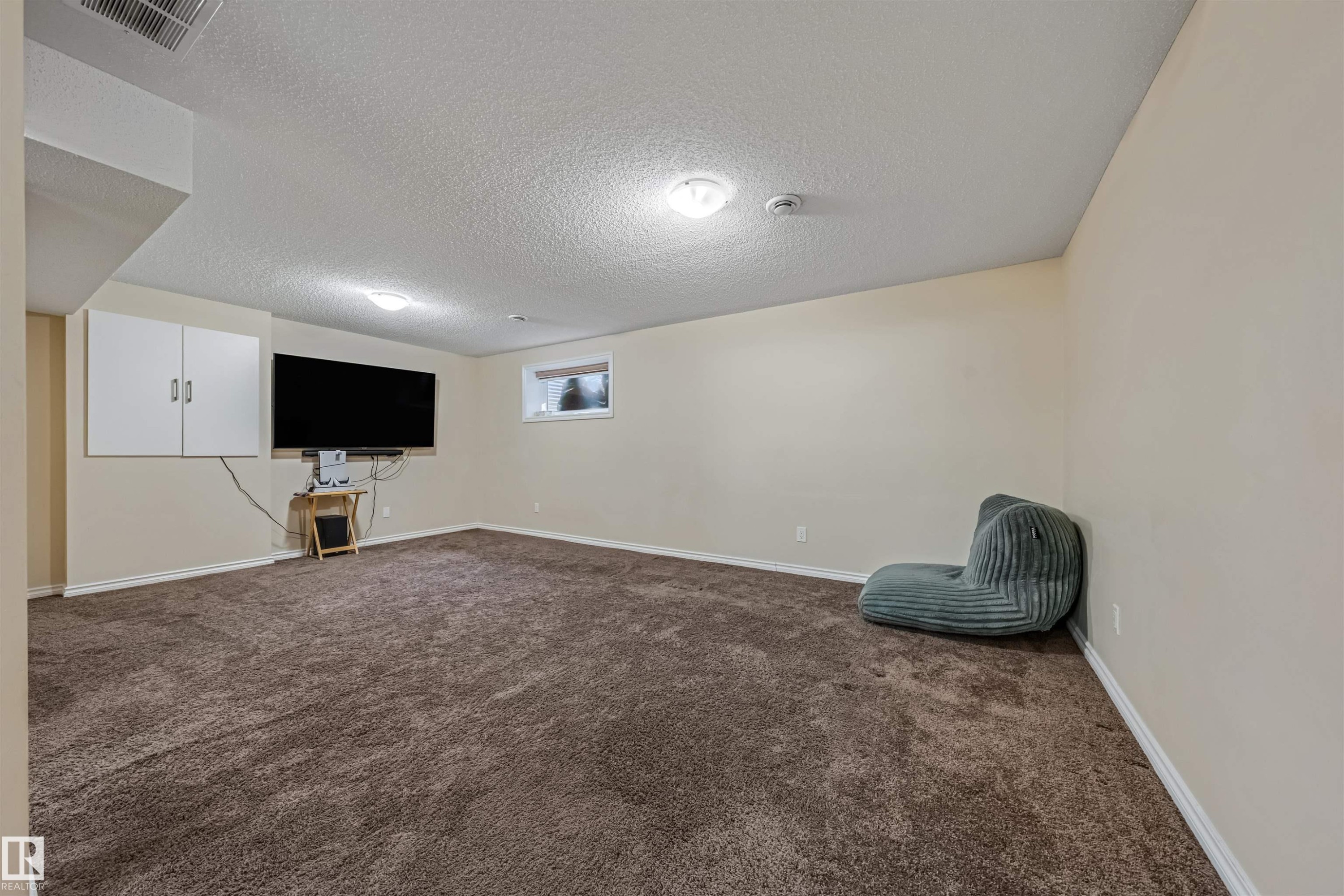 Spacious room featuring neutral-toned walls, brown carpeting, recessed lighting, and a window providing natural light - 2314 22 Avenue, Edmonton, AB - Indoor