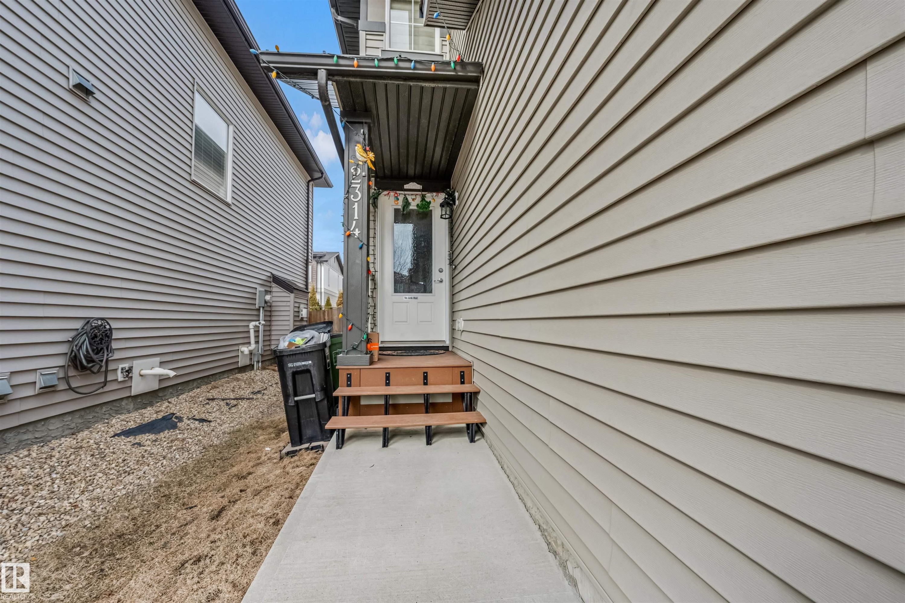 Side entrance featuring a white panel door, wooden steps, and a concrete pathway - 2314 22 Avenue, Edmonton, AB - Outdoor With Exterior