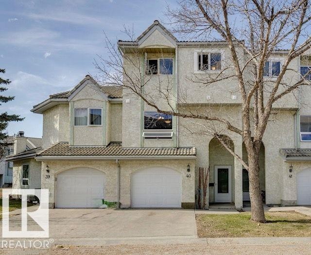 Stucco exterior featuring multiple arched garage doors, a recessed front entry, and a multi-level roofline - 40 9520 174 Street, Edmonton, AB - Outdoor