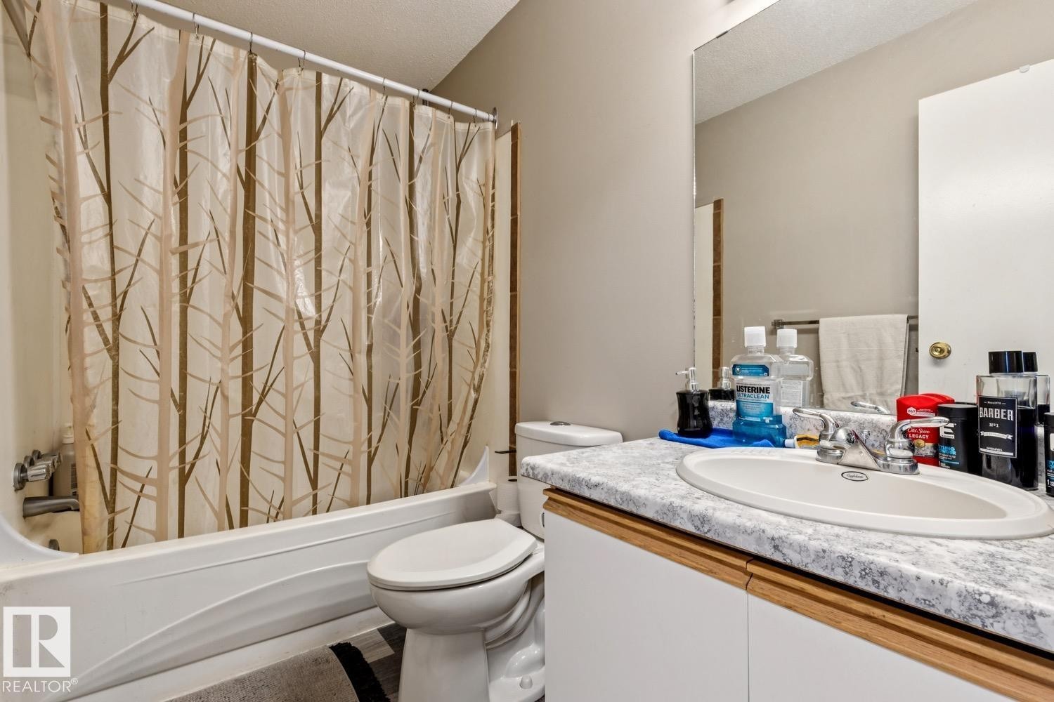 Full bathroom featuring a white tub, toilet, and vanity with a laminate countertop and an integrated sink - 40 9520 174 Street, Edmonton, AB - Indoor Photo Showing Bathroom