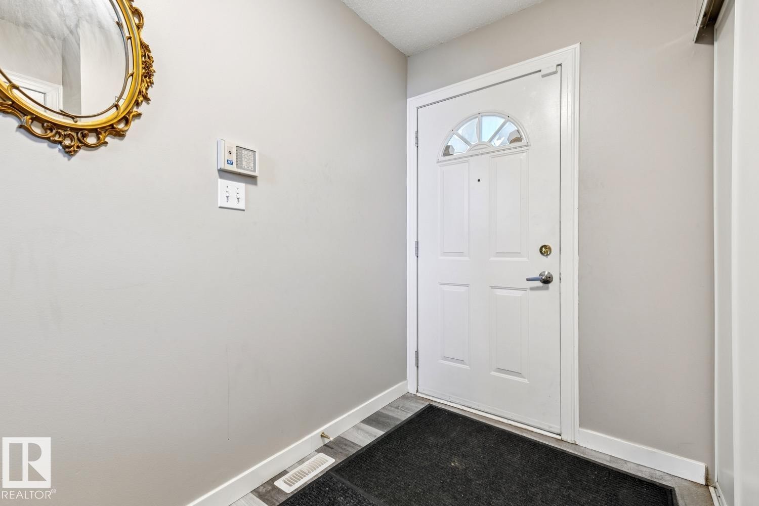 Entryway featuring a white paneled door with an arched glass insert, light grey walls, and wood-finish flooring - 40 9520 174 Street, Edmonton, AB - Indoor Photo Showing Other Room