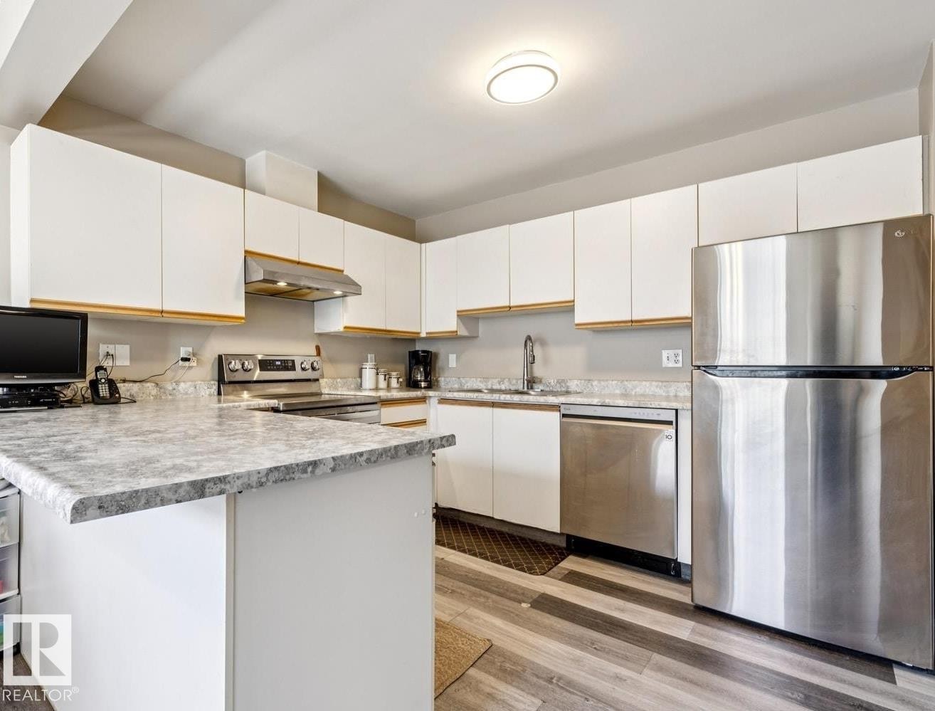 Bright kitchen featuring white cabinetry, grey-patterned countertops, stainless steel appliances, and wood-finish flooring - 40 9520 174 Street, Edmonton, AB - Indoor Photo Showing Kitchen With Stainless Steel Kitchen