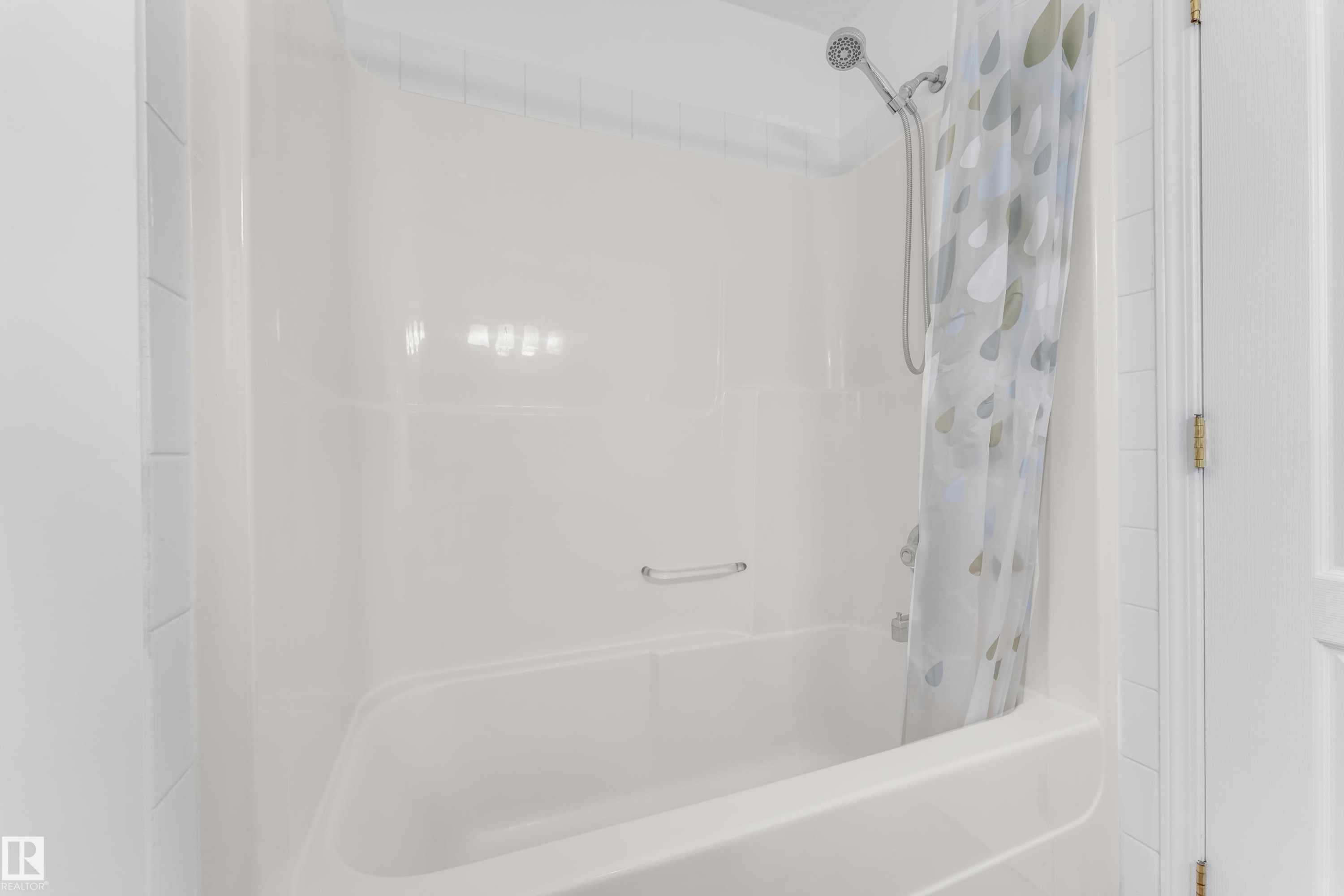 White fiberglass tub and shower combination with a flexible shower head fixture - 4103 37A Avenue, Edmonton, AB - Indoor Photo Showing Bathroom