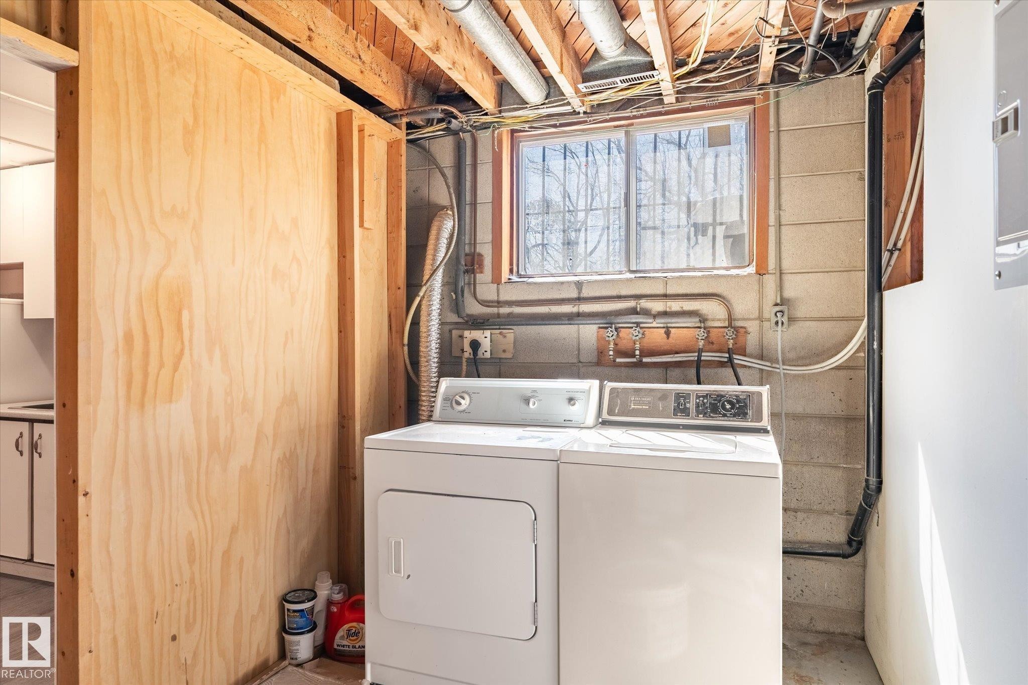 Basement laundry area with exposed wood ceiling joists and block wall construction - 10531 128 Avenue, Edmonton, AB - Indoor Photo Showing Laundry Room