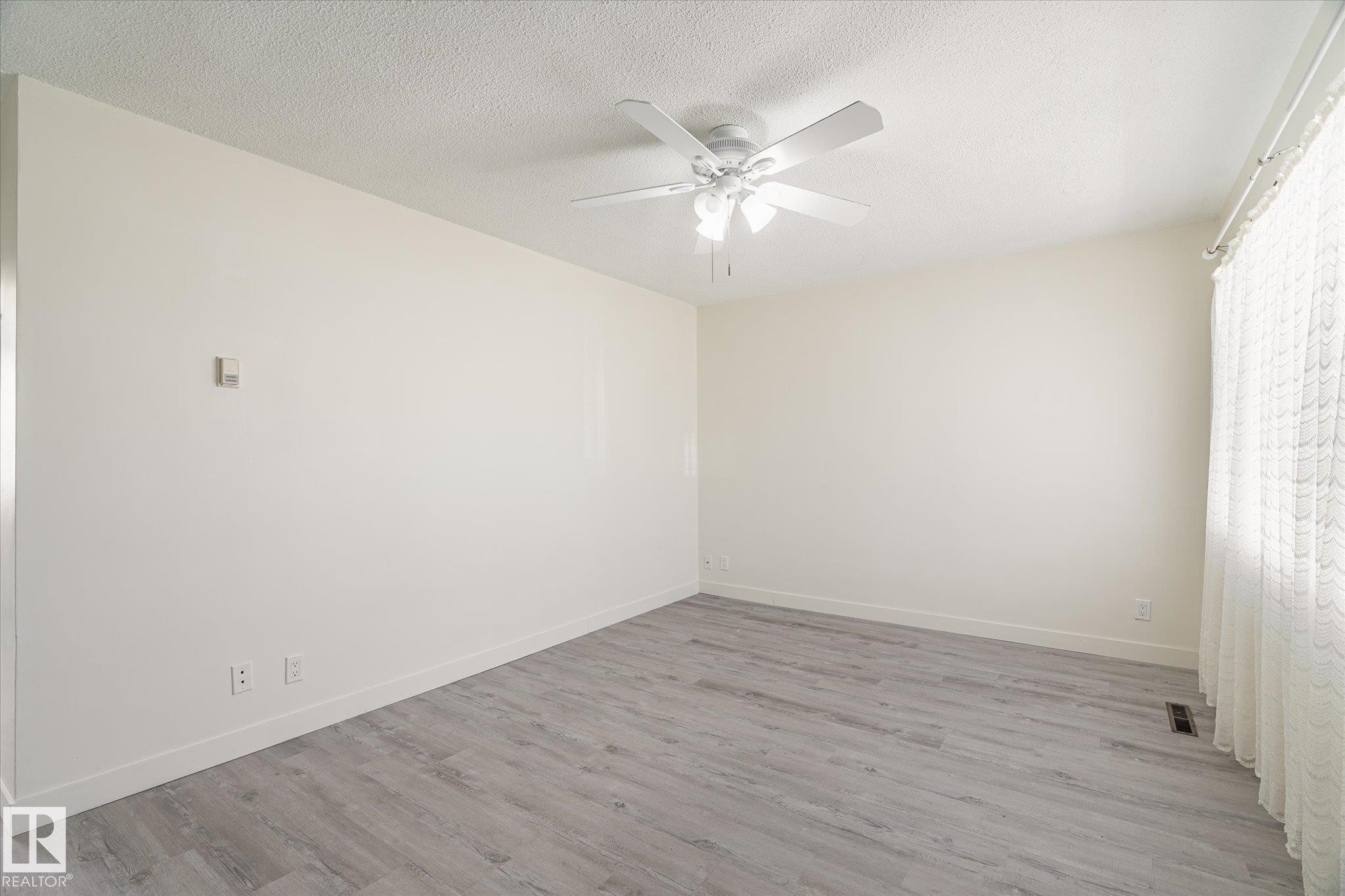 Interior room featuring light-toned walls, wood-finish flooring, and white baseboards - 10531 128 Avenue, Edmonton, AB - Indoor Photo Showing Other Room