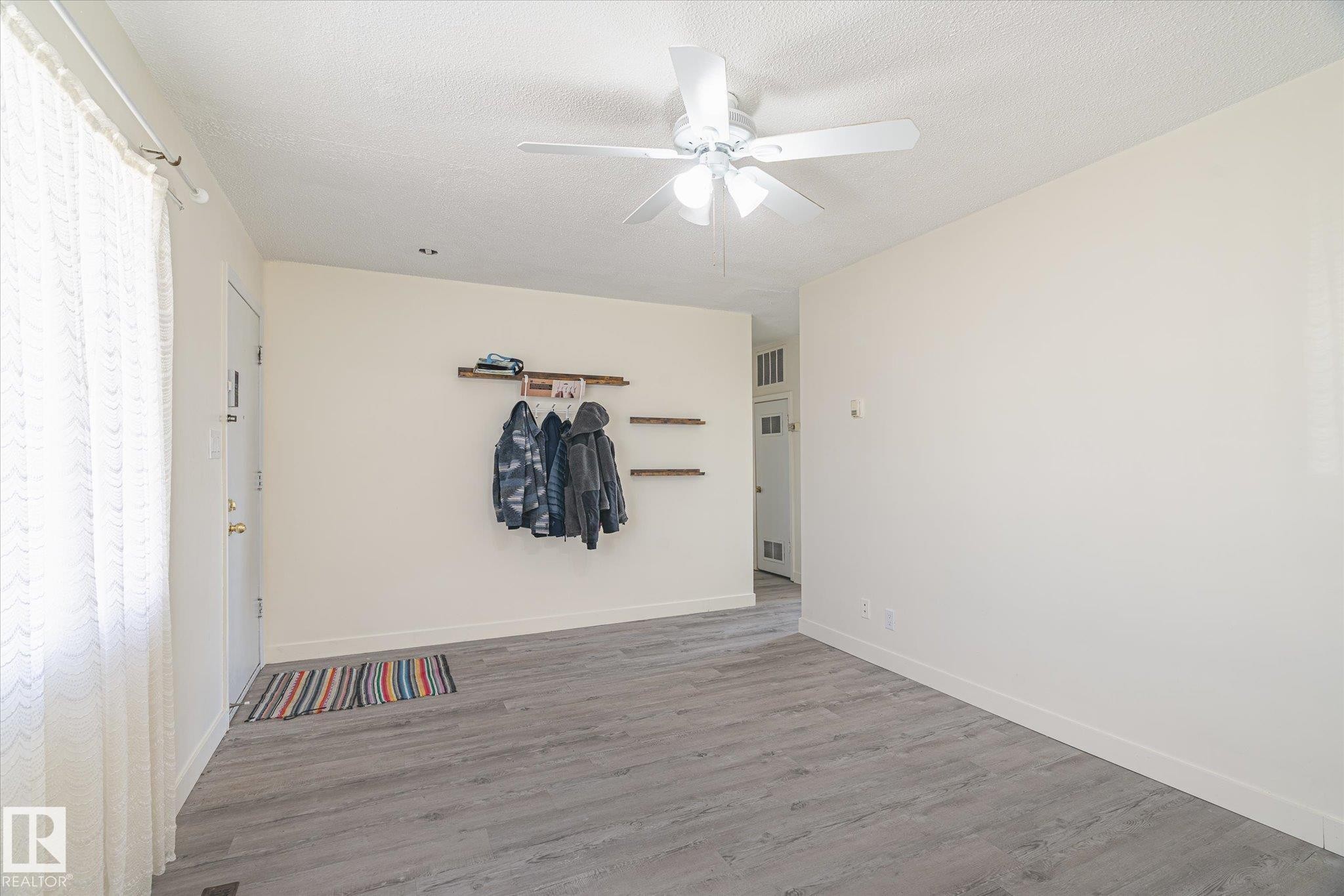 Entry area featuring wood-finish flooring, a ceiling fan with integrated lighting, and neutral wall tones - 10531 128 Avenue, Edmonton, AB - Indoor Photo Showing Other Room