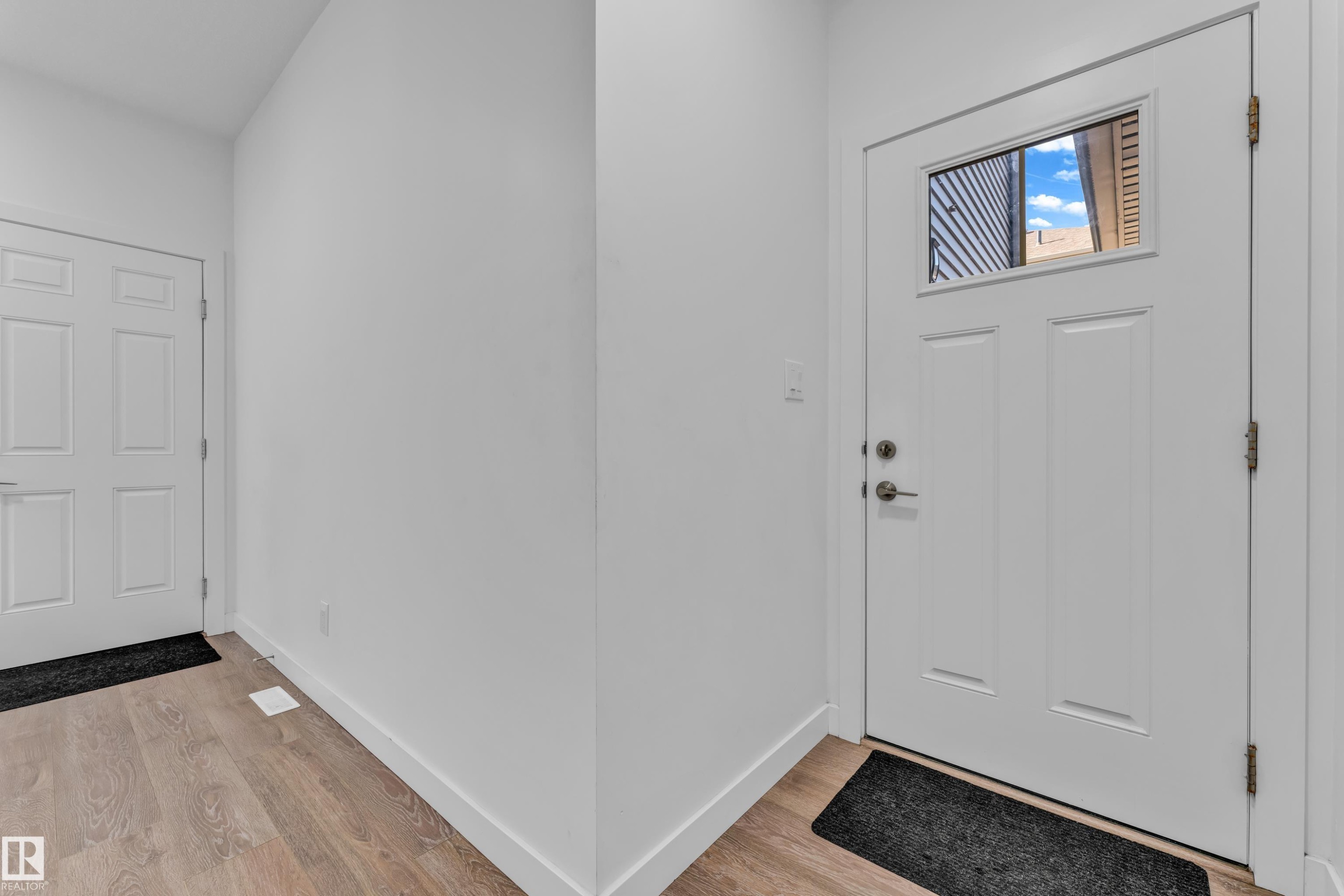 Entry foyer featuring a paneled door with an upper window, wood-finish flooring, and crisp white trim - 41 603 Orchards Boulevard, Edmonton, AB - Indoor Photo Showing Other Room