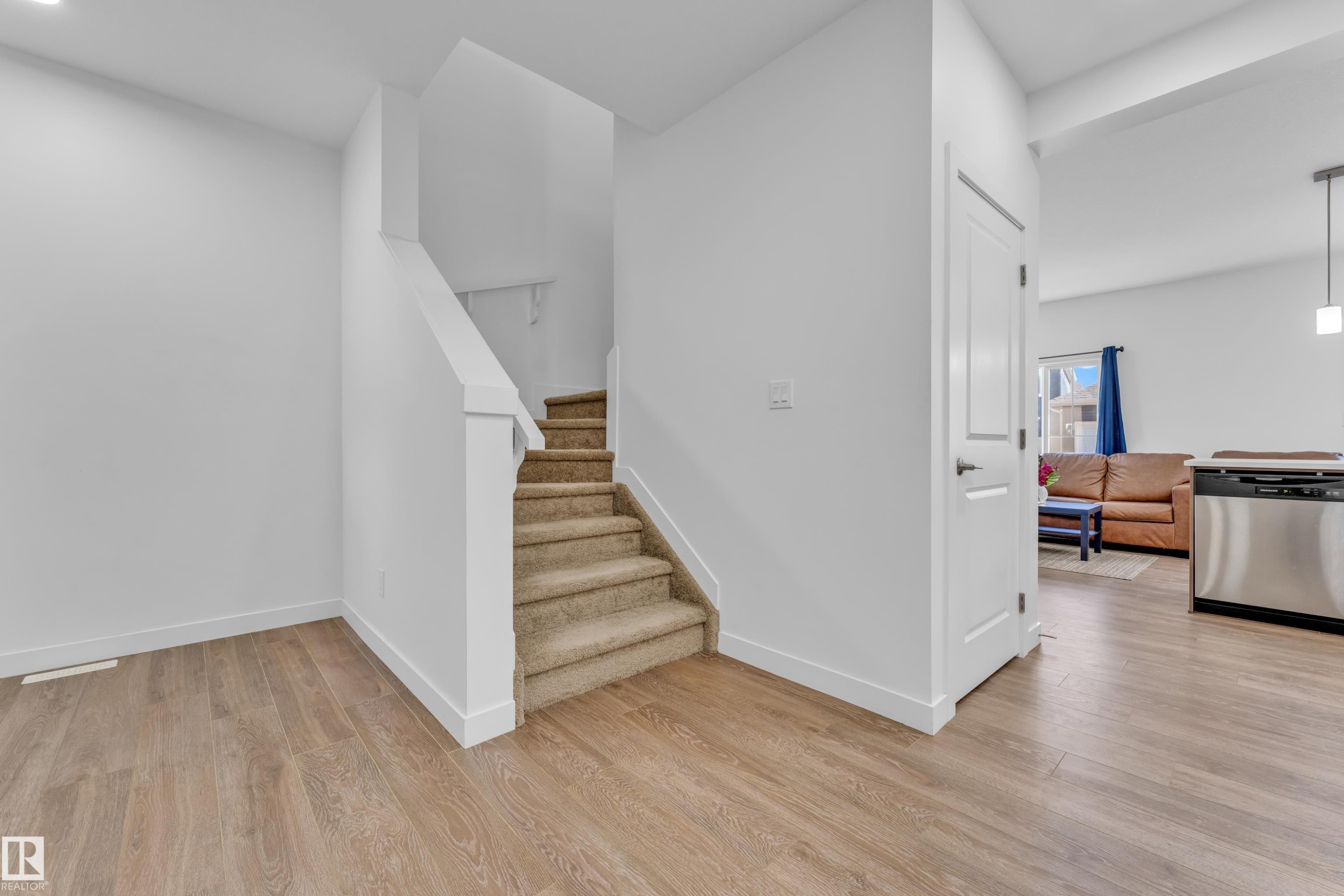 Warm wood-finish flooring extending from the entryway - 41 603 Orchards Boulevard, Edmonton, AB - Indoor Photo Showing Other Room