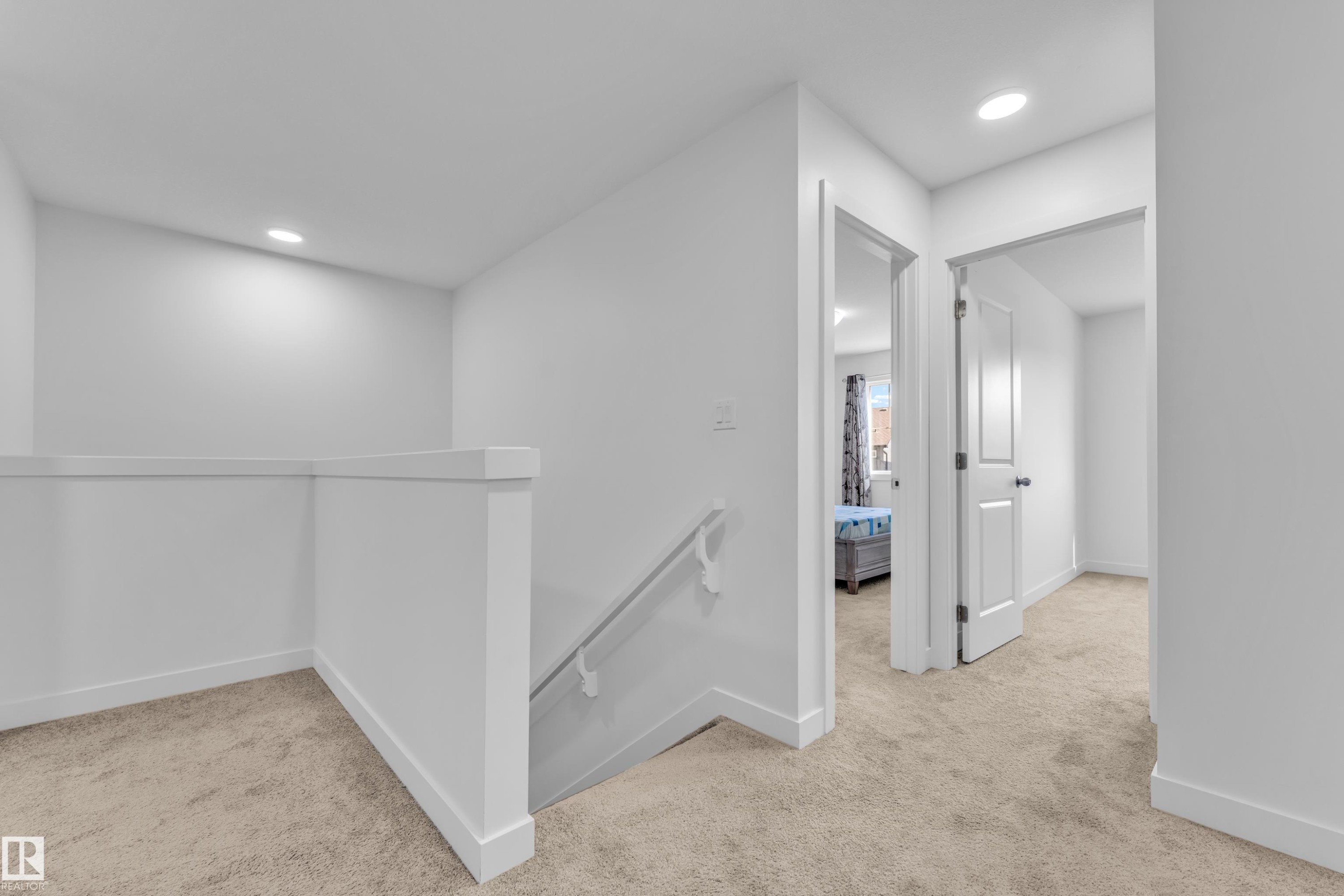 Carpeted hallway with a white painted railing and recessed lighting - 41 603 Orchards Boulevard, Edmonton, AB - Indoor Photo Showing Other Room