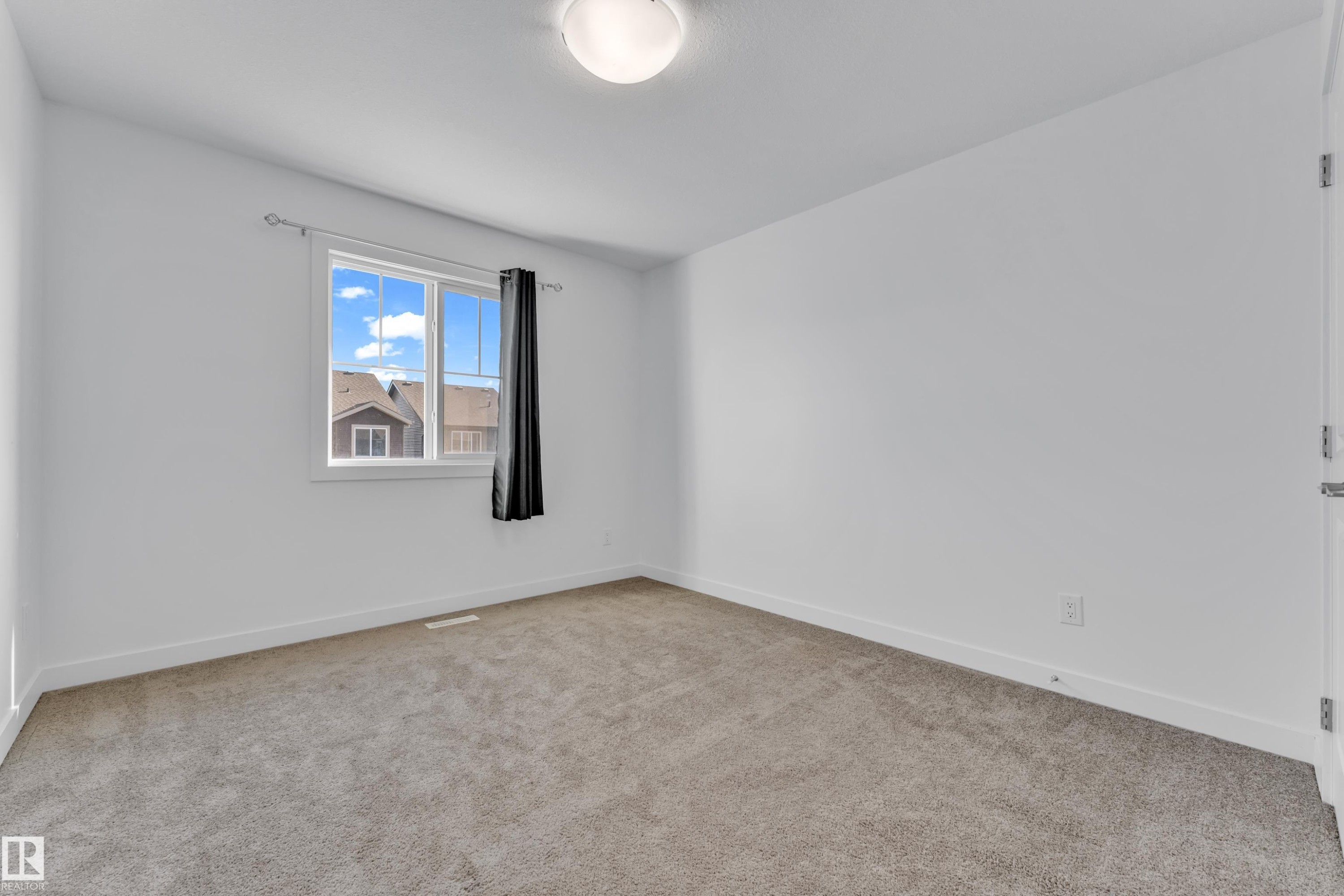 Bright room featuring a window with white trim, gray carpet flooring, white baseboards, and a flush mount ceiling light fixture - 41 603 Orchards Boulevard, Edmonton, AB - Indoor Photo Showing Other Room