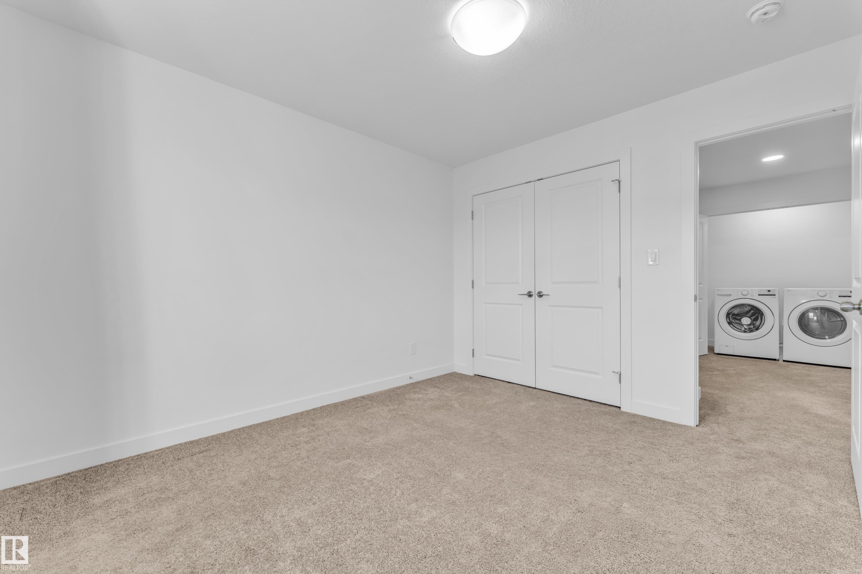 Neutral toned carpeted room with white walls and a white bi-fold closet door - 41 603 Orchards Boulevard, Edmonton, AB - Indoor