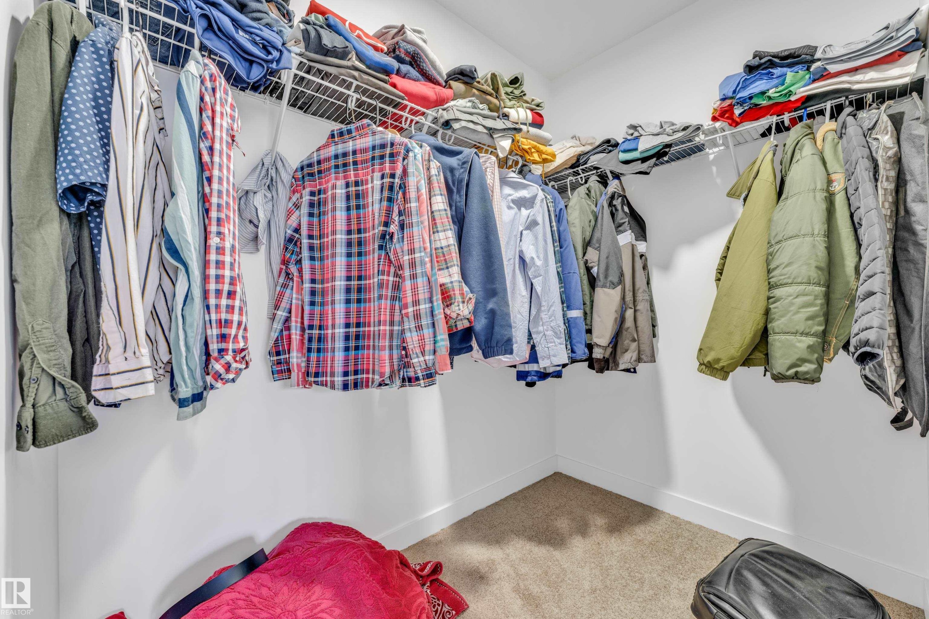 Walk-in closet featuring white wire shelving, hanging rods, and light-colored carpet flooring - 41 603 Orchards Boulevard, Edmonton, AB - Indoor With Storage