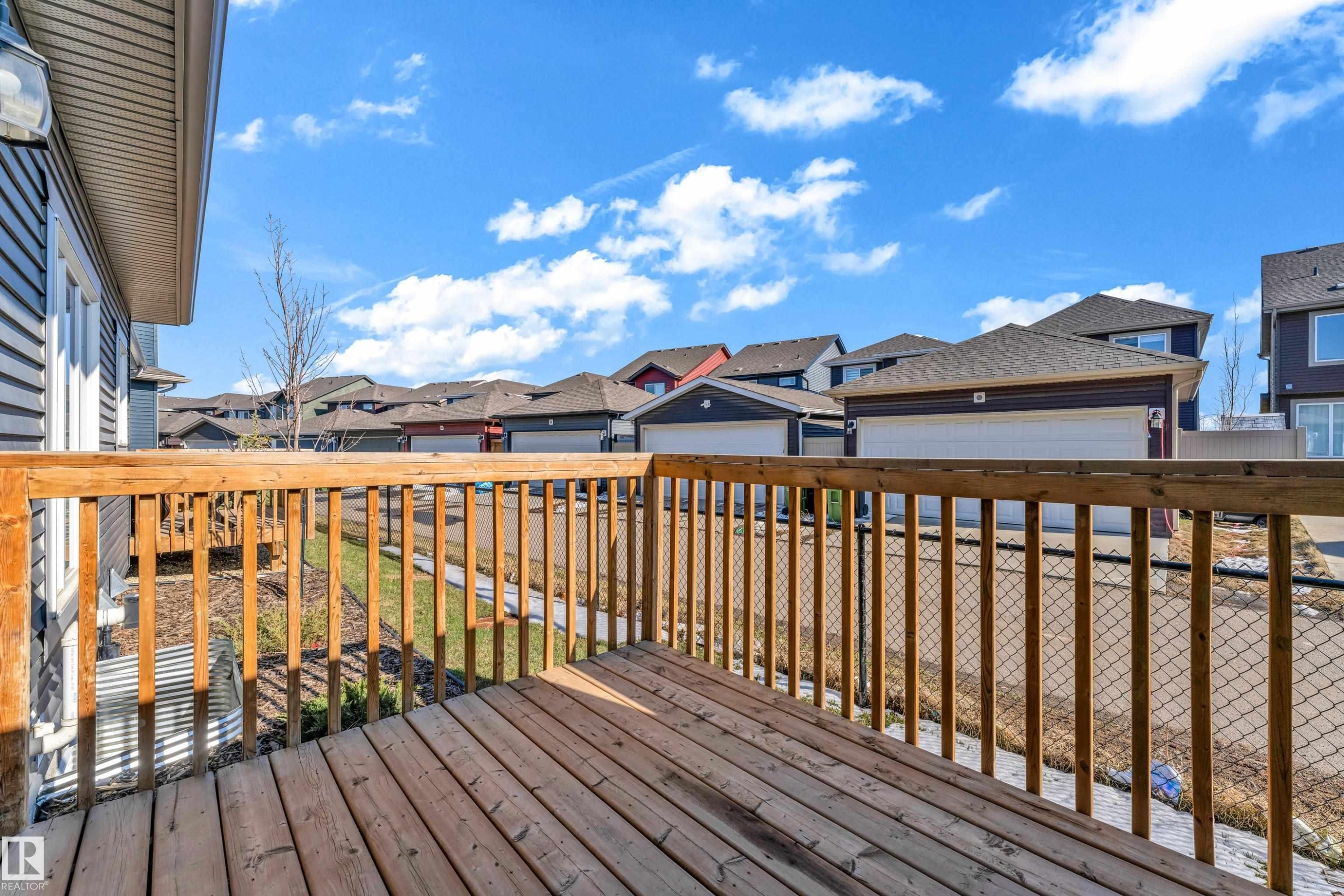 Expansive wood-finish deck with wooden railings, featuring a chain-link fence below and siding exterior - 41 603 Orchards Boulevard, Edmonton, AB - Outdoor