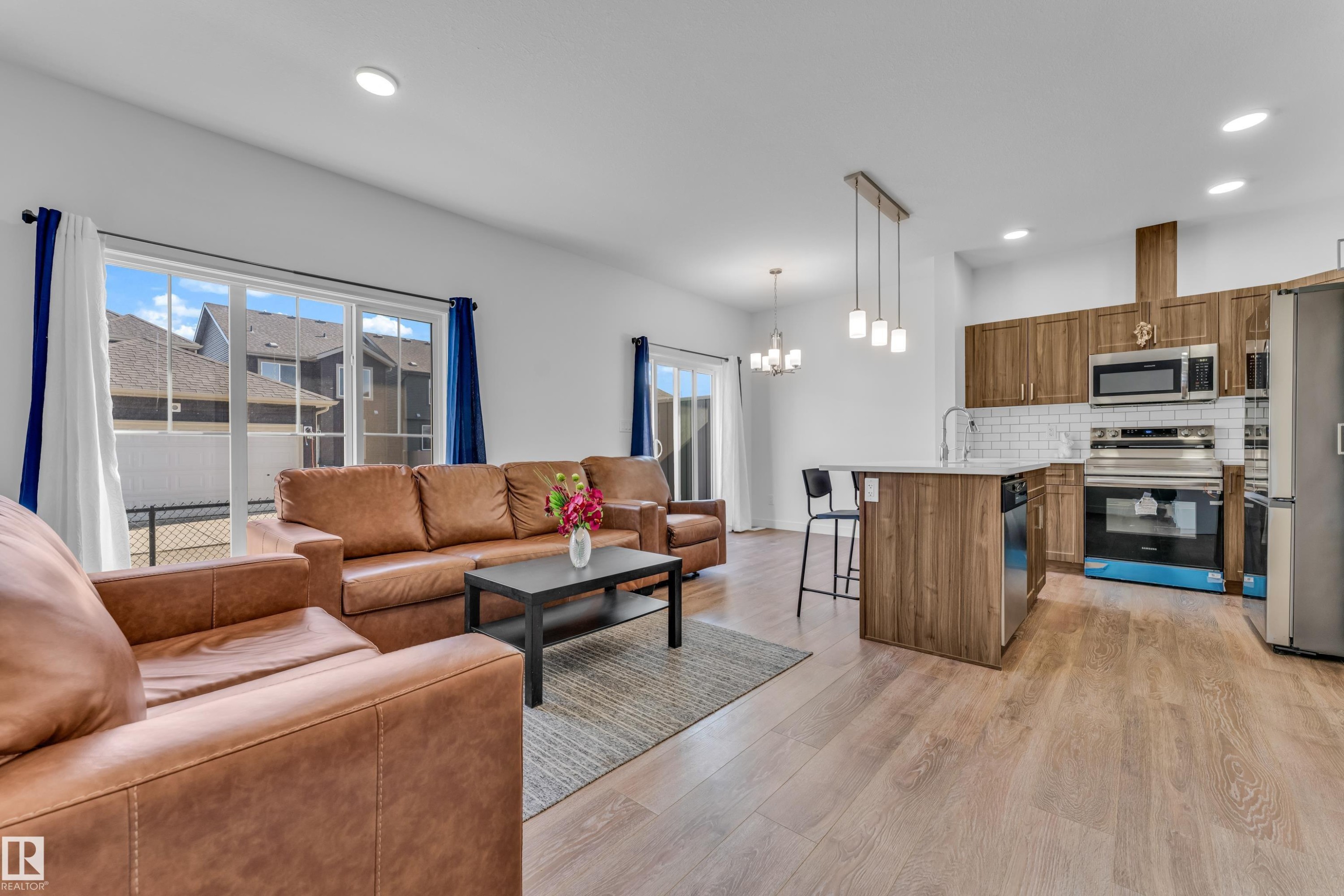 Open-concept living area featuring wood-finish flooring, recessed lighting, and a sliding glass door - 41 603 Orchards Boulevard, Edmonton, AB - Indoor