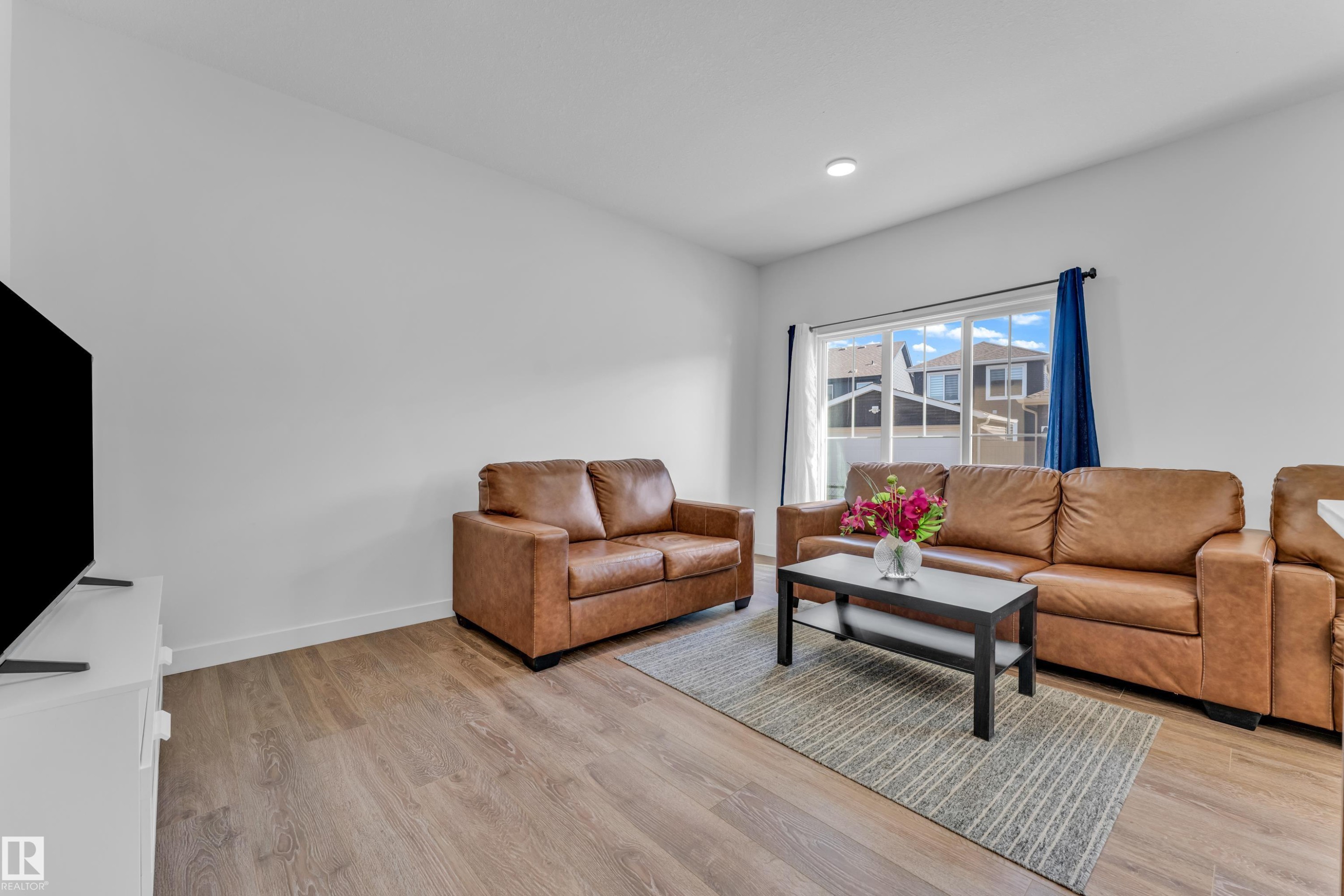Open-concept living space with wood-finish flooring, recessed lighting, and a large window - 41 603 Orchards Boulevard, Edmonton, AB - Indoor Photo Showing Living Room