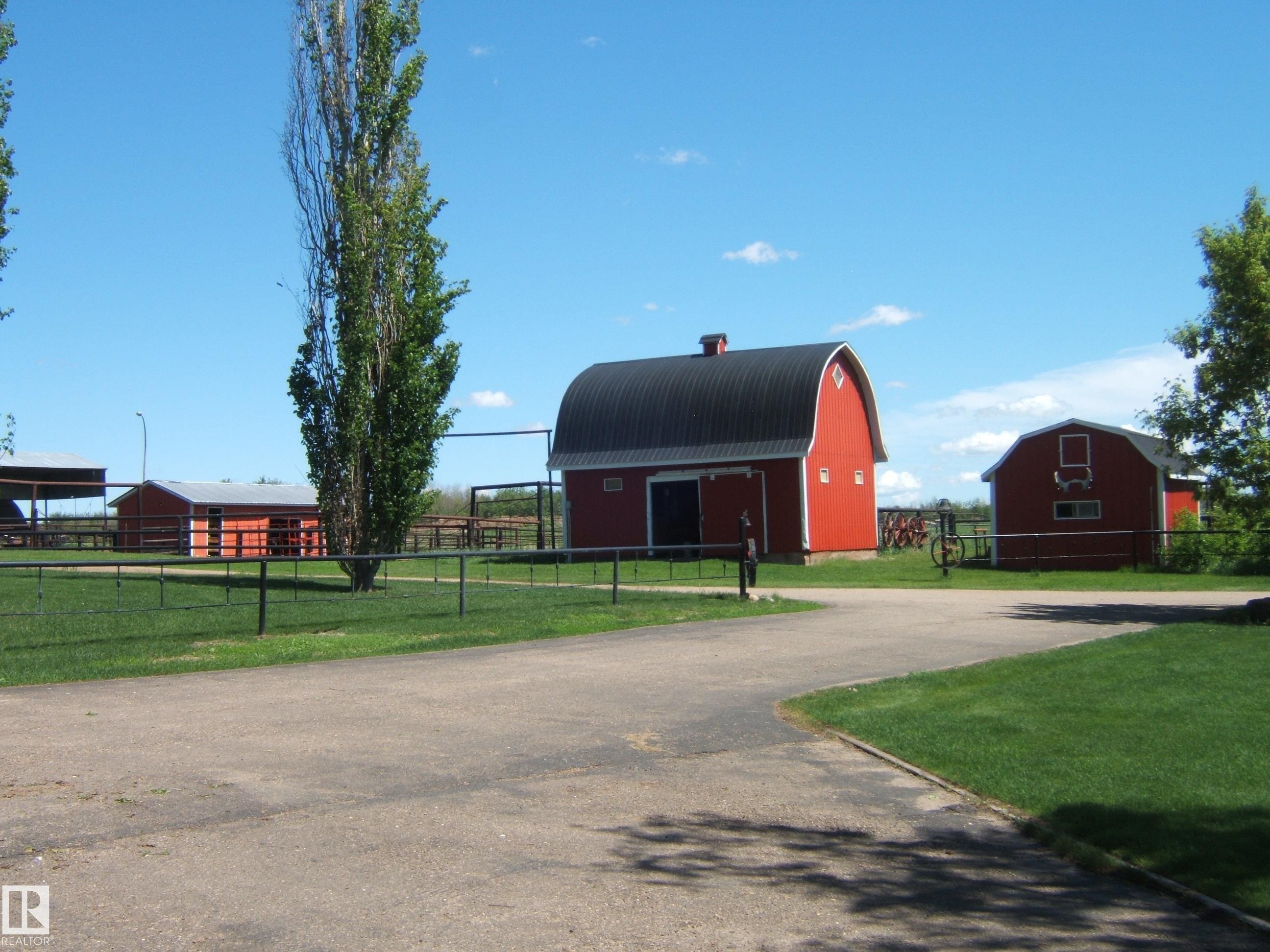 Red barn structures featuring a metal gambrel roof and white trim accents - 123064 Hwy 45, Rural Two Hills County, AB