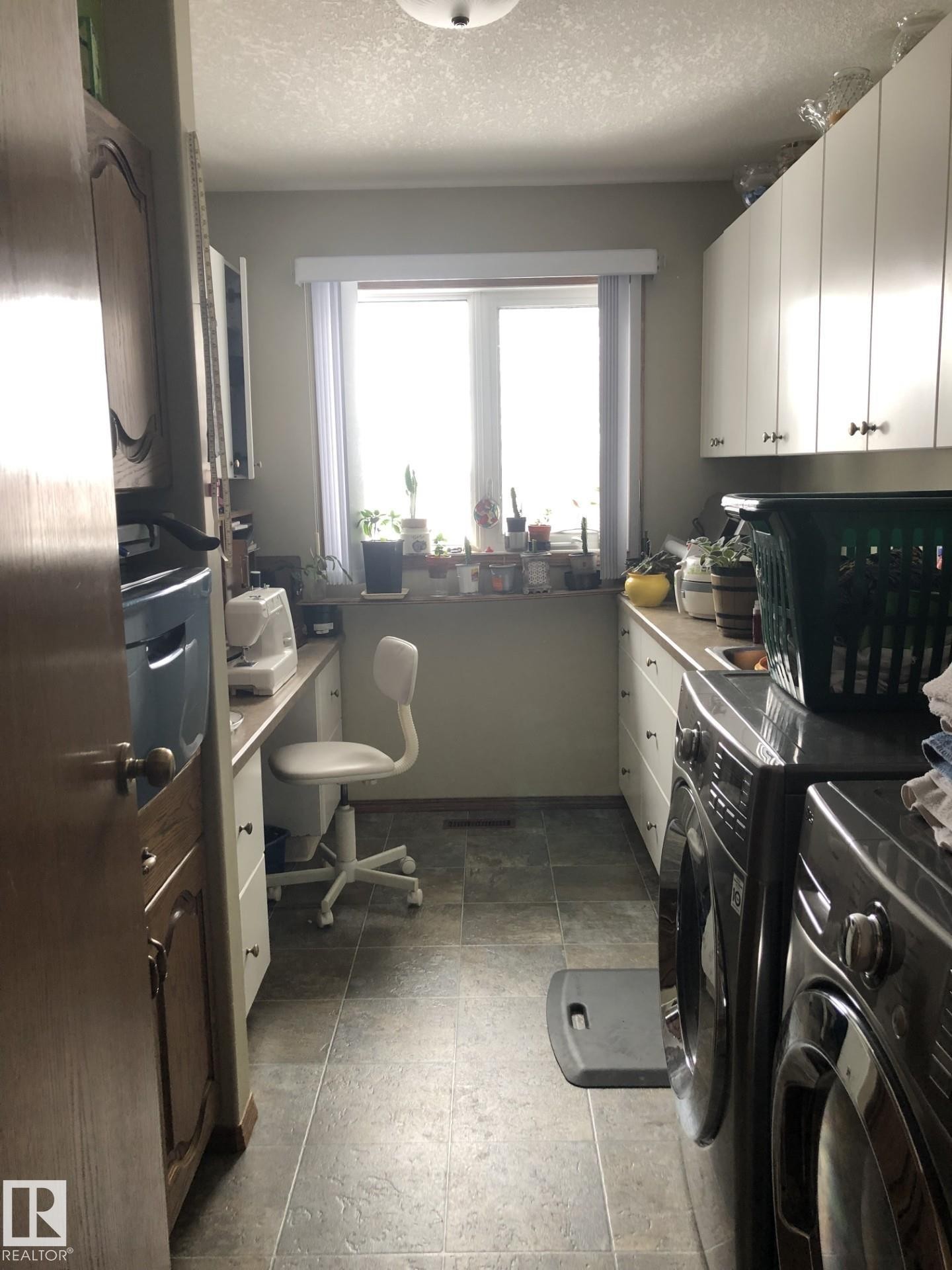 Utility room featuring a window with natural light, a built-in countertop, ample white cabinetry, and tile flooring - 123064 Hwy 45, Rural Two Hills County, AB
