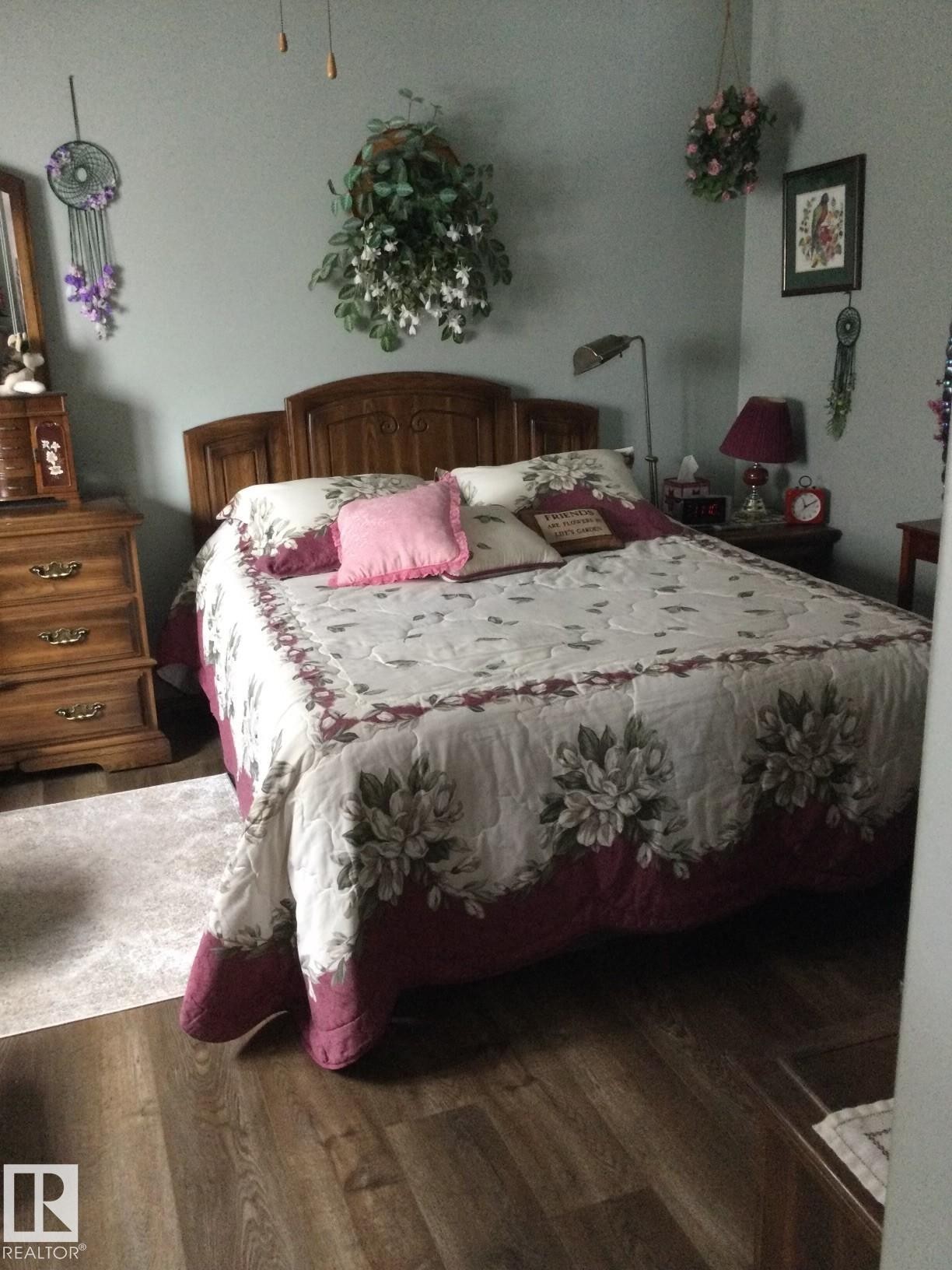 Bedroom featuring wood-finish flooring, a decorative headboard, and a ceiling fan - 123064 Hwy 45, Rural Two Hills County, AB