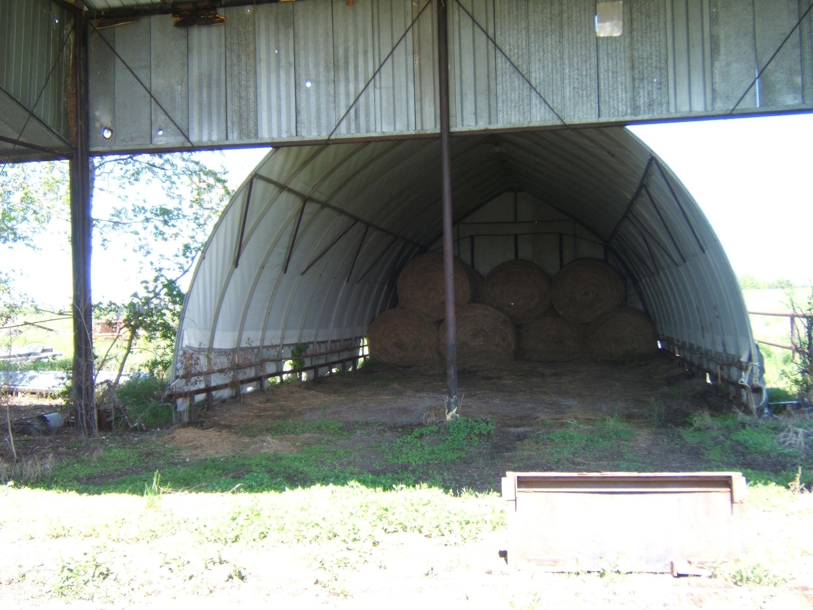 Quonset hut-style barn with a corrugated metal roof and a partial wood fence base - 123064 Hwy 45, Rural Two Hills County, AB