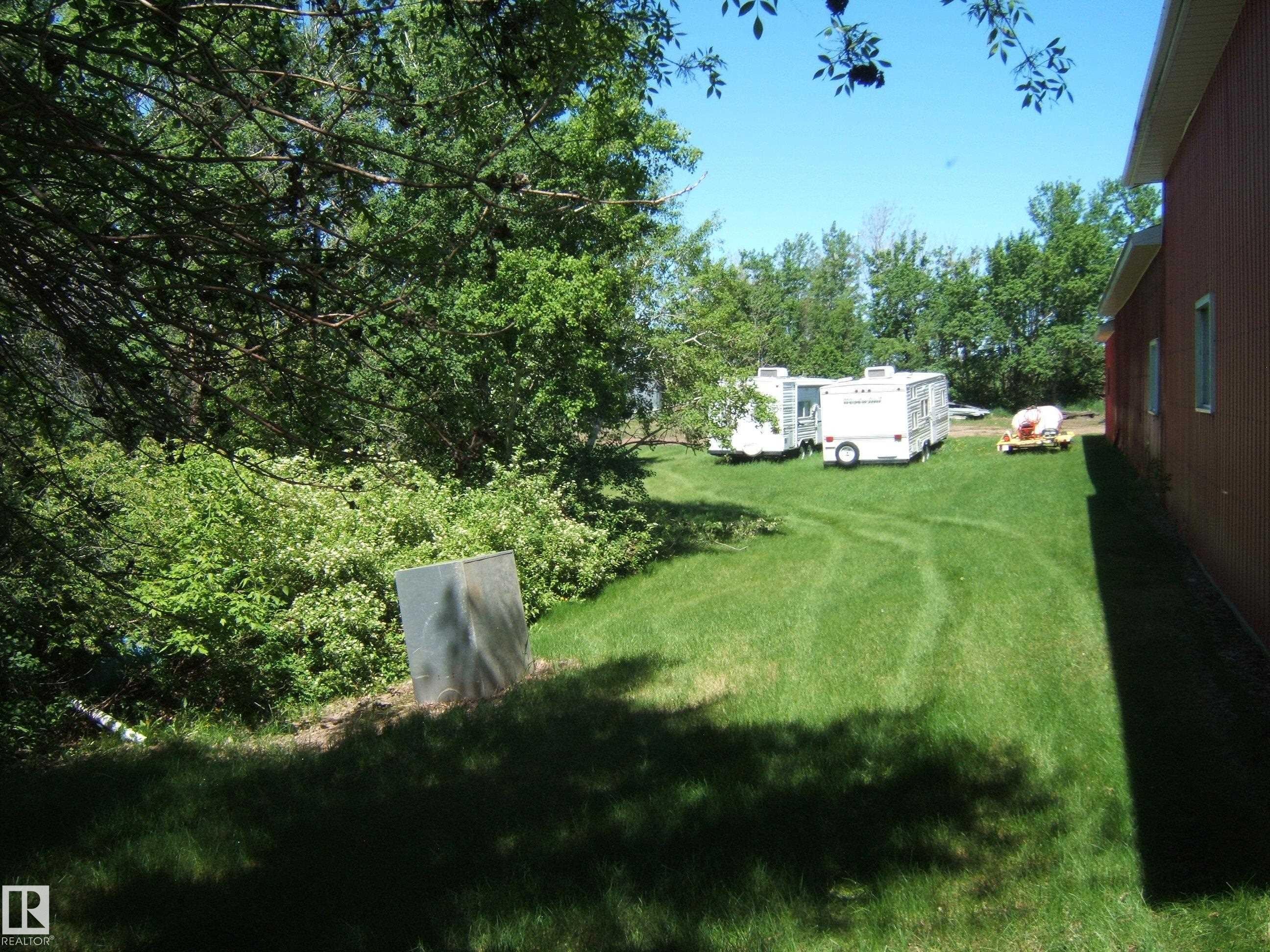 Expansive green lawn bordering a red-sided structure - 123064 Hwy 45, Rural Two Hills County, AB