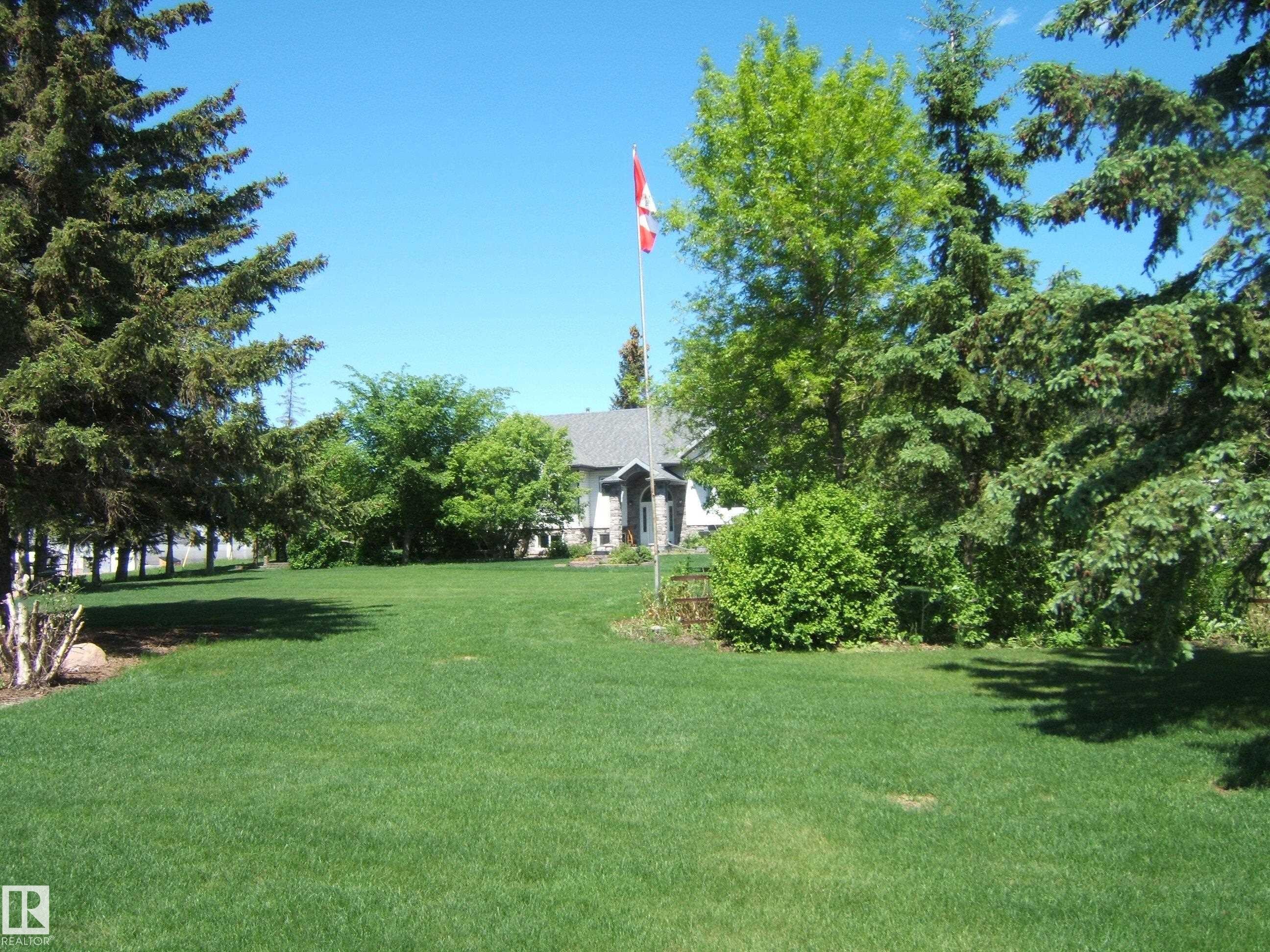 Expansive green lawn framed by mature evergreen trees - 123064 Hwy 45, Rural Two Hills County, AB