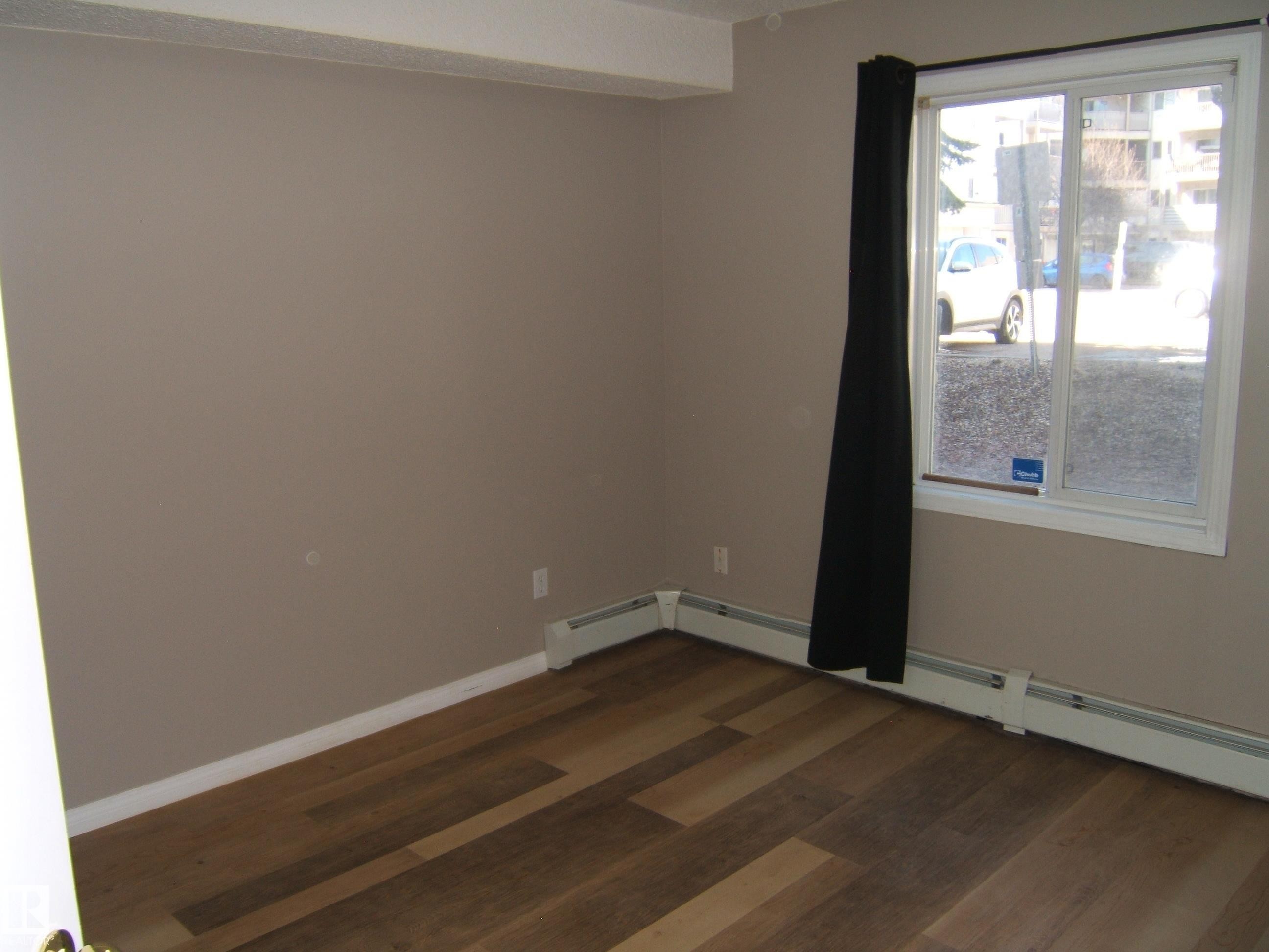 Room featuring wood-finish flooring, neutral wall tones, and white trim - 105 11214 80 Street, Edmonton, AB - Indoor Photo Showing Other Room