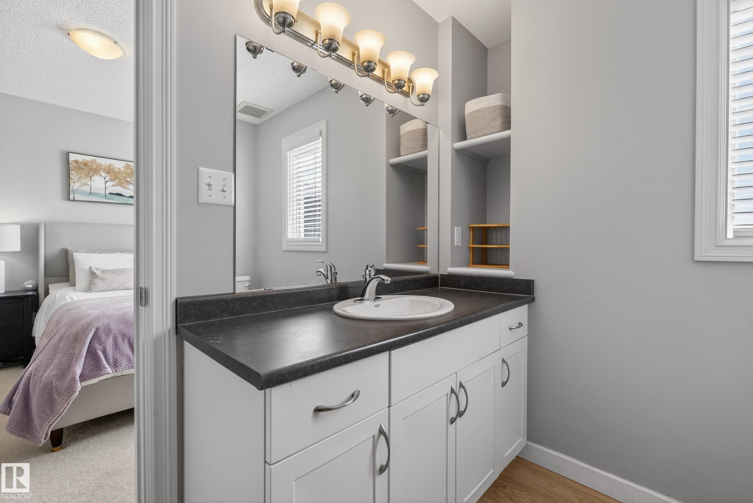 Bathroom vanity with a single basin sink, dark countertop, and brushed nickel faucet - 1148 35 Avenue, Edmonton, AB - Indoor Photo Showing Bathroom