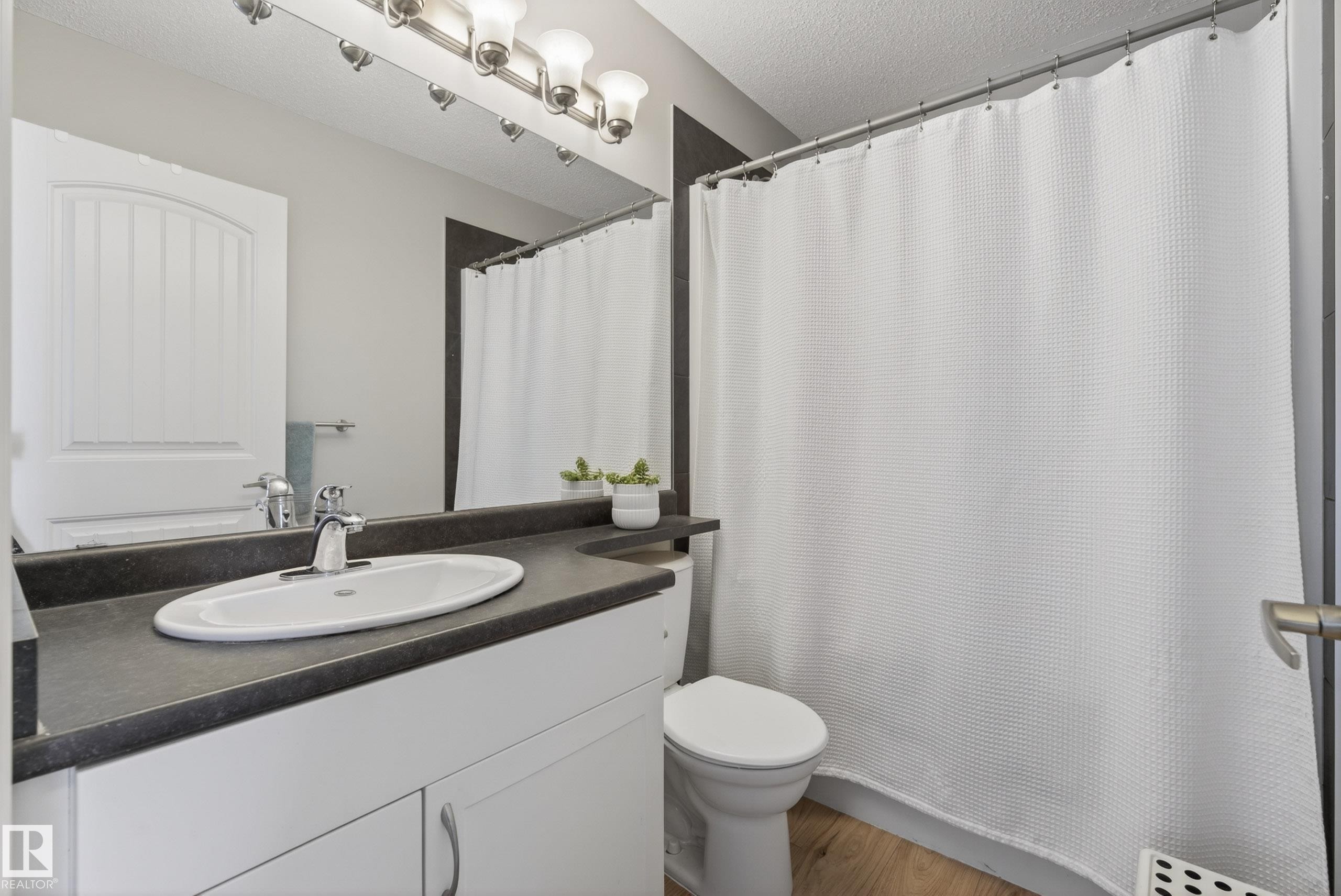 Bathroom featuring a white vanity with a dark countertop, an oval undermount sink, and brushed nickel fixtures - 1148 35 Avenue, Edmonton, AB - Indoor Photo Showing Bathroom