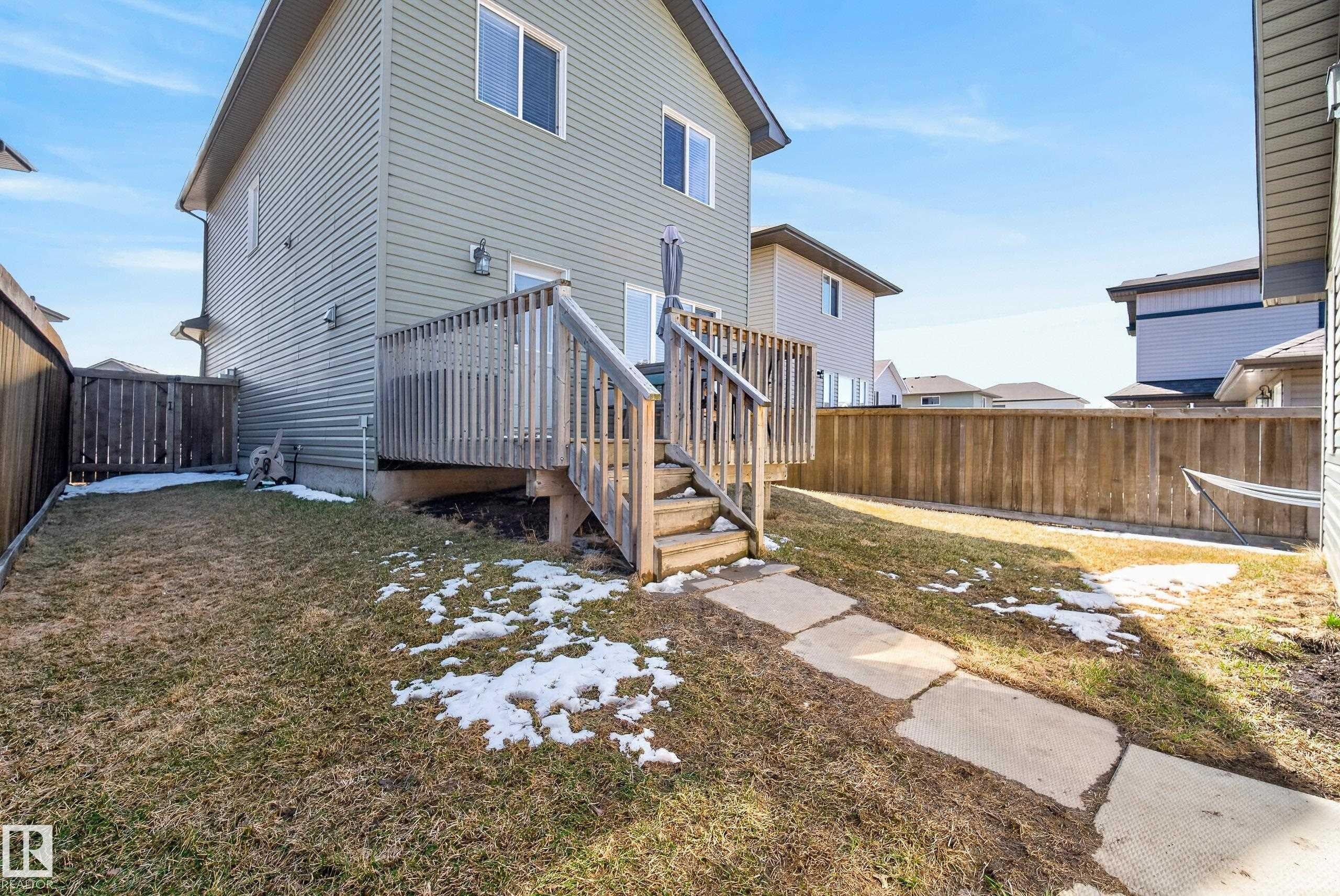 Rear exterior featuring a wood deck with stairs, a concrete paver pathway, and wood privacy fencing - 1148 35 Avenue, Edmonton, AB - Outdoor With Exterior