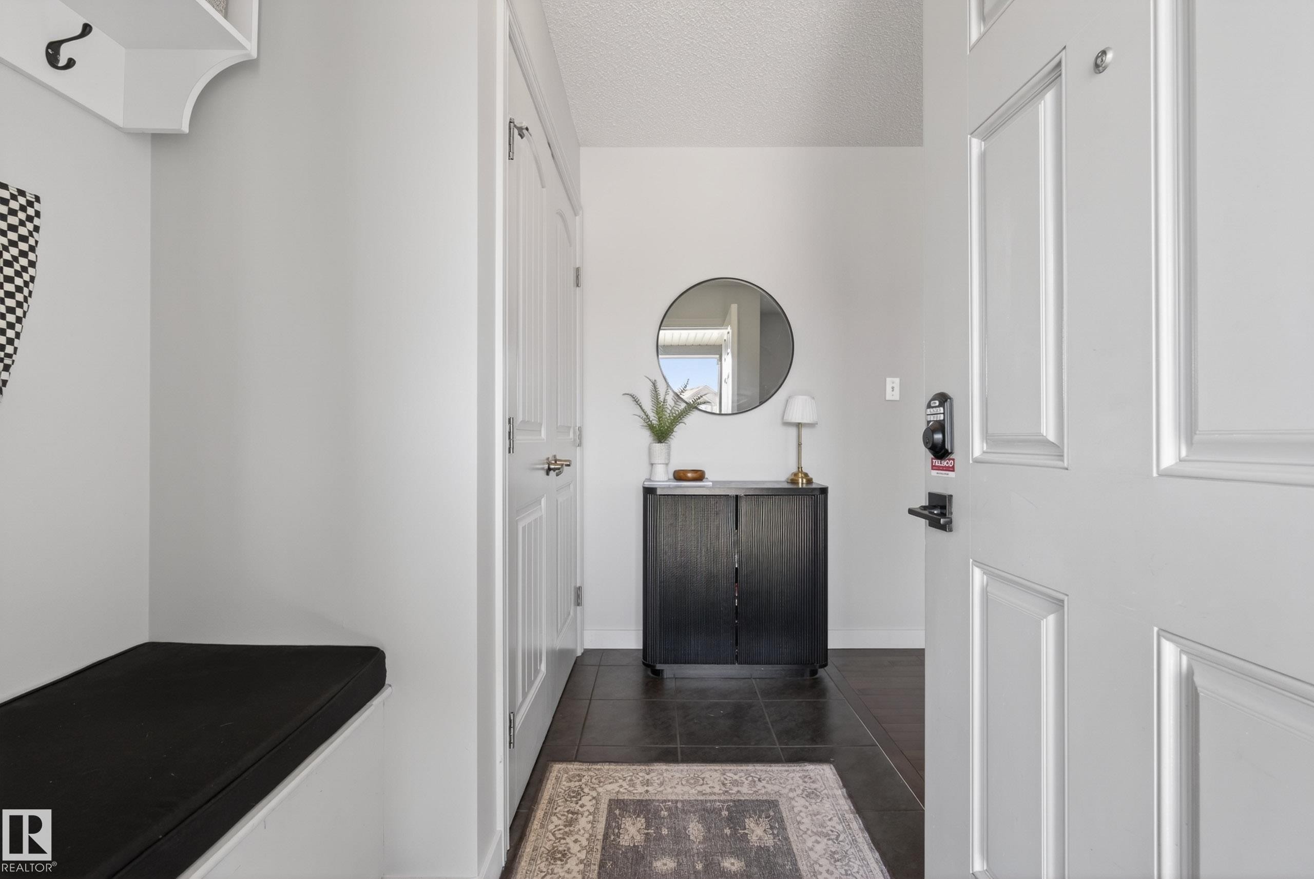 Welcoming entryway featuring a paneled entry door, built-in bench with cushion, dark tile flooring, and a storage console - 1148 35 Avenue, Edmonton, AB - Indoor Photo Showing Other Room