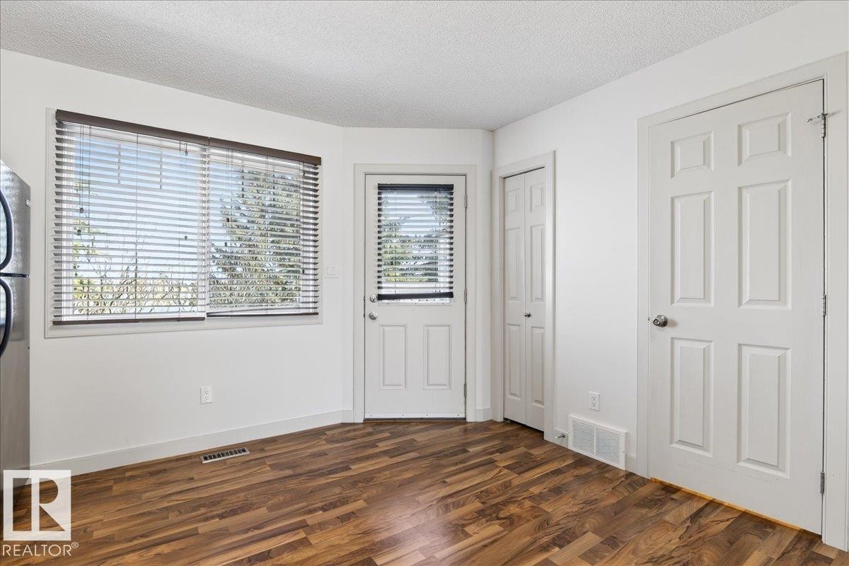 Hardwood-finish flooring complementing white walls and trim - 18 6032 38 Avenue, Edmonton, AB - Indoor Photo Showing Other Room