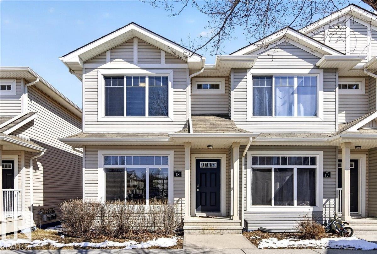 Light-toned siding exterior featuring multiple gables and a dark entry door with decorative glass - 18 6032 38 Avenue, Edmonton, AB - Outdoor With Facade