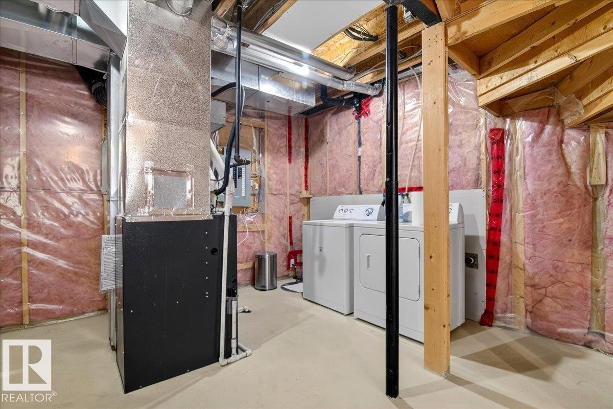 Utility area featuring a furnace, laundry appliances, exposed joists, and insulated walls - 18 6032 38 Avenue, Edmonton, AB - Indoor Photo Showing Laundry Room