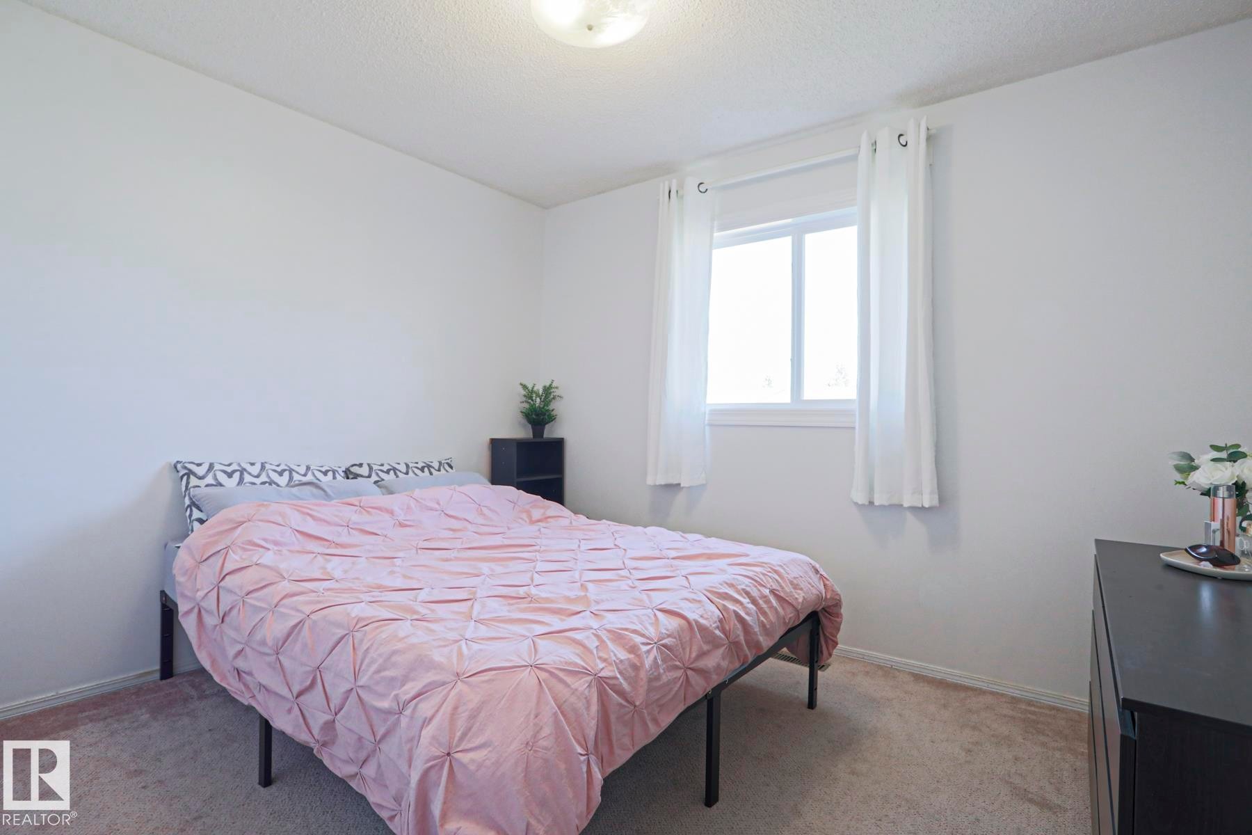 Room featuring a large window with white trim, light-colored walls, and neutral carpeting - 2433 89 Street, Edmonton, AB - Indoor Photo Showing Bedroom