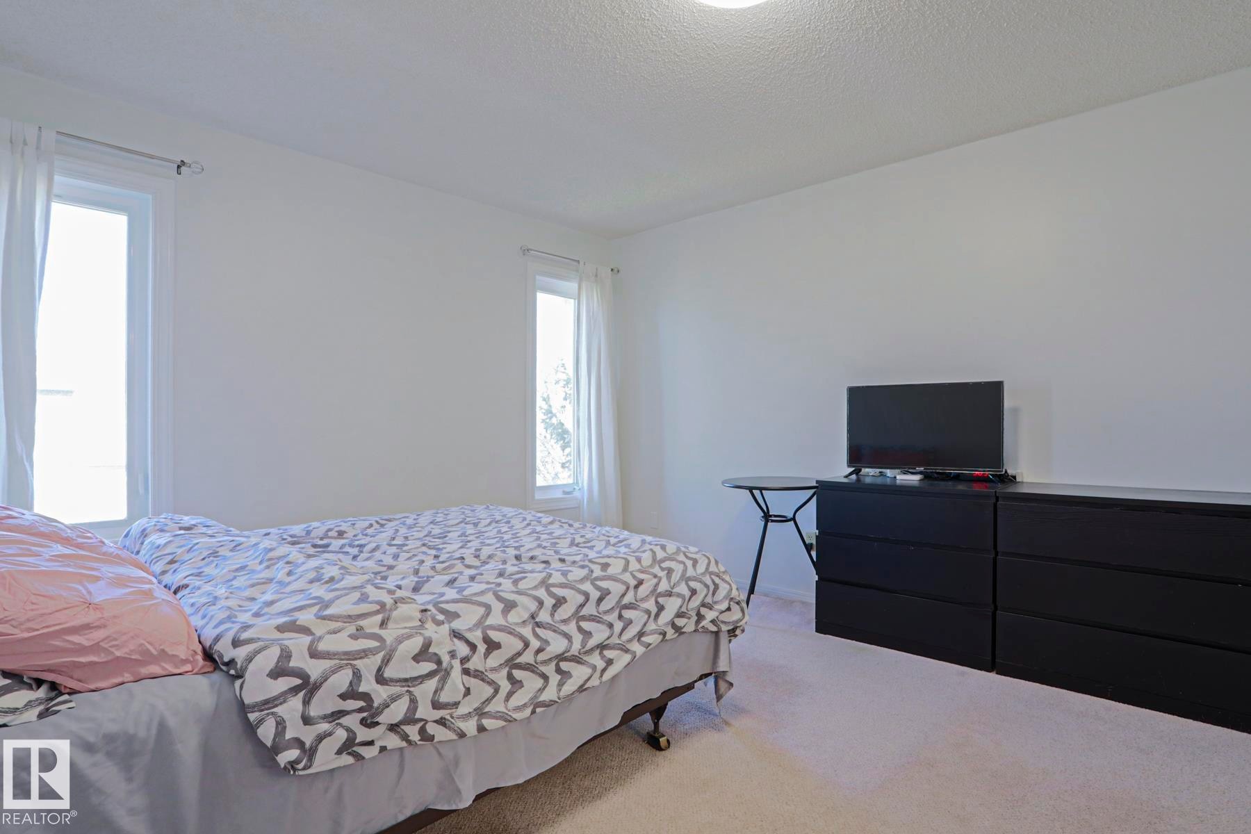 Bright room with two vertical windows featuring light-colored window treatments - 2433 89 Street, Edmonton, AB - Indoor Photo Showing Bedroom