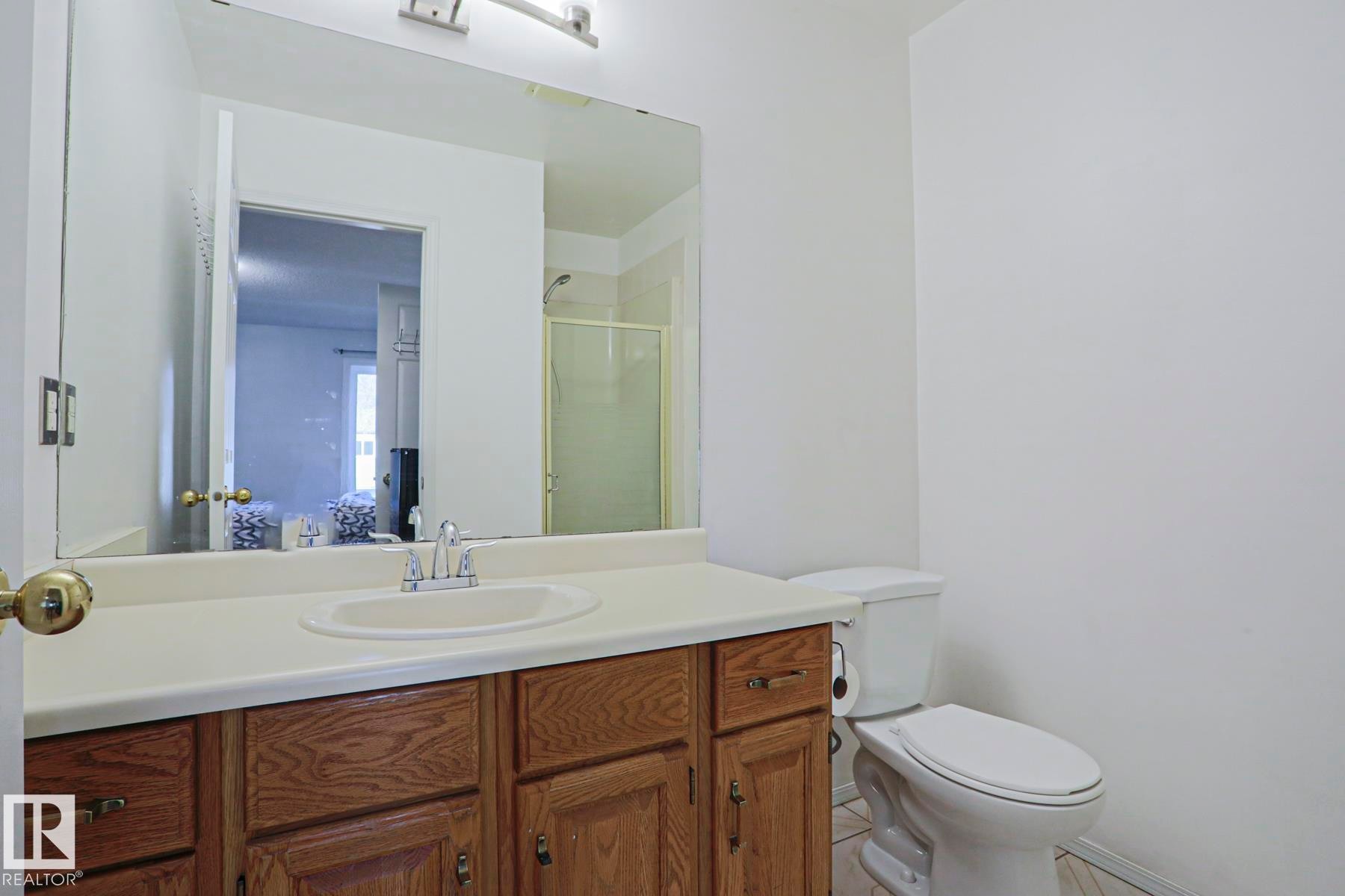 Bathroom featuring a wood-finish vanity with a light-colored countertop and an integrated sink - 2433 89 Street, Edmonton, AB - Indoor Photo Showing Bathroom