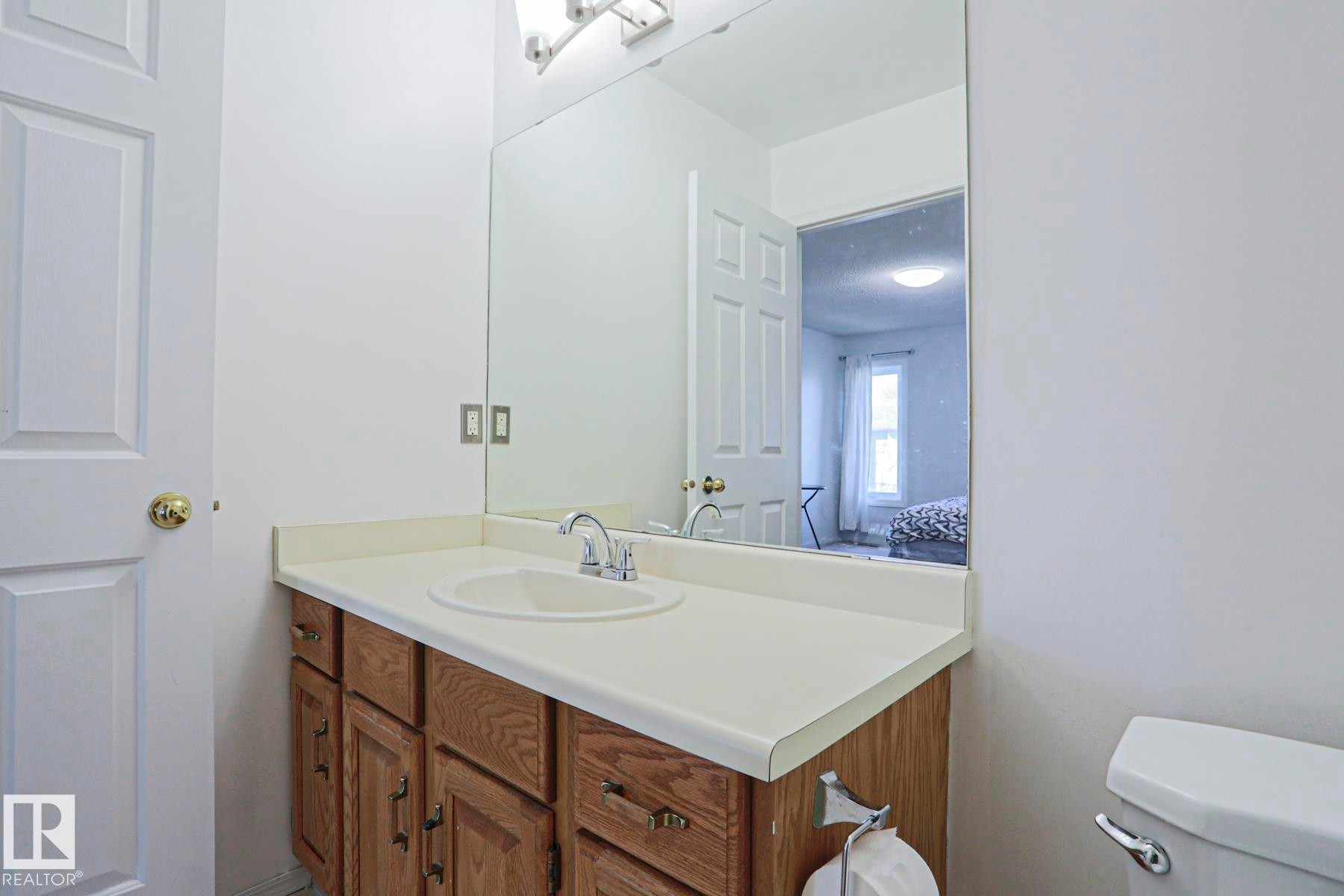 Bathroom vanity featuring a light-toned countertop with an integrated sink and chrome faucet - 2433 89 Street, Edmonton, AB - Indoor Photo Showing Bathroom