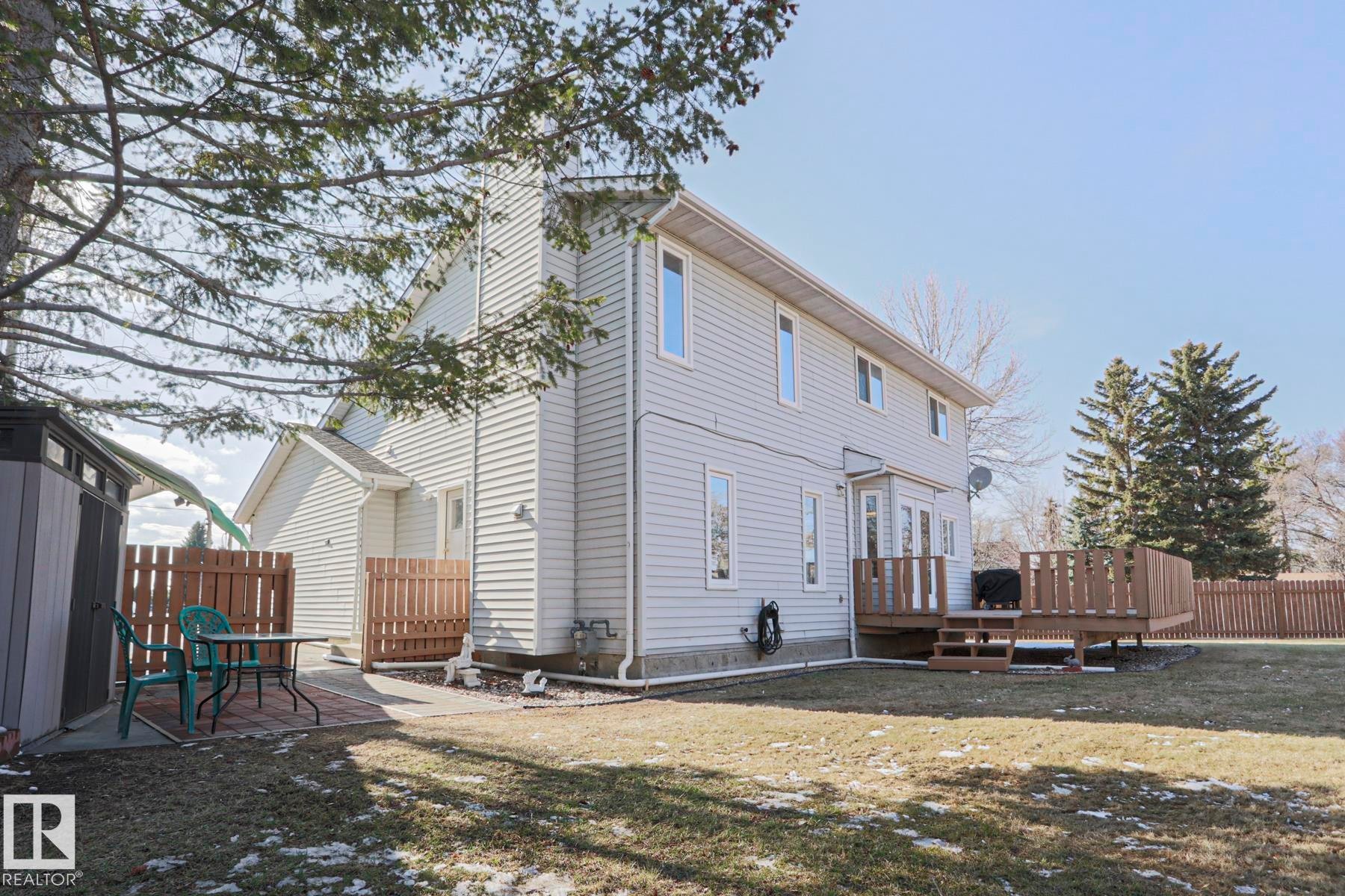 Expansive backyard featuring a large wooden deck, privacy fencing, and a paved patio area - 2433 89 Street, Edmonton, AB - Outdoor