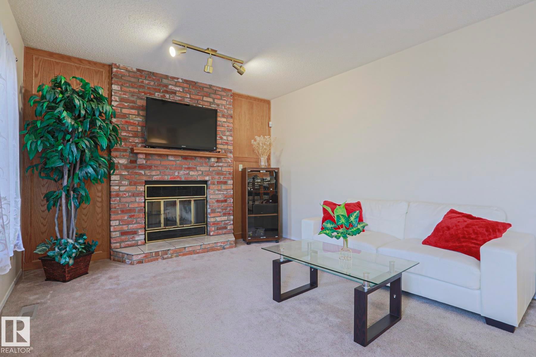 Living room featuring a brick fireplace with a wood mantle - 2433 89 Street, Edmonton, AB - Indoor Photo Showing Living Room With Fireplace